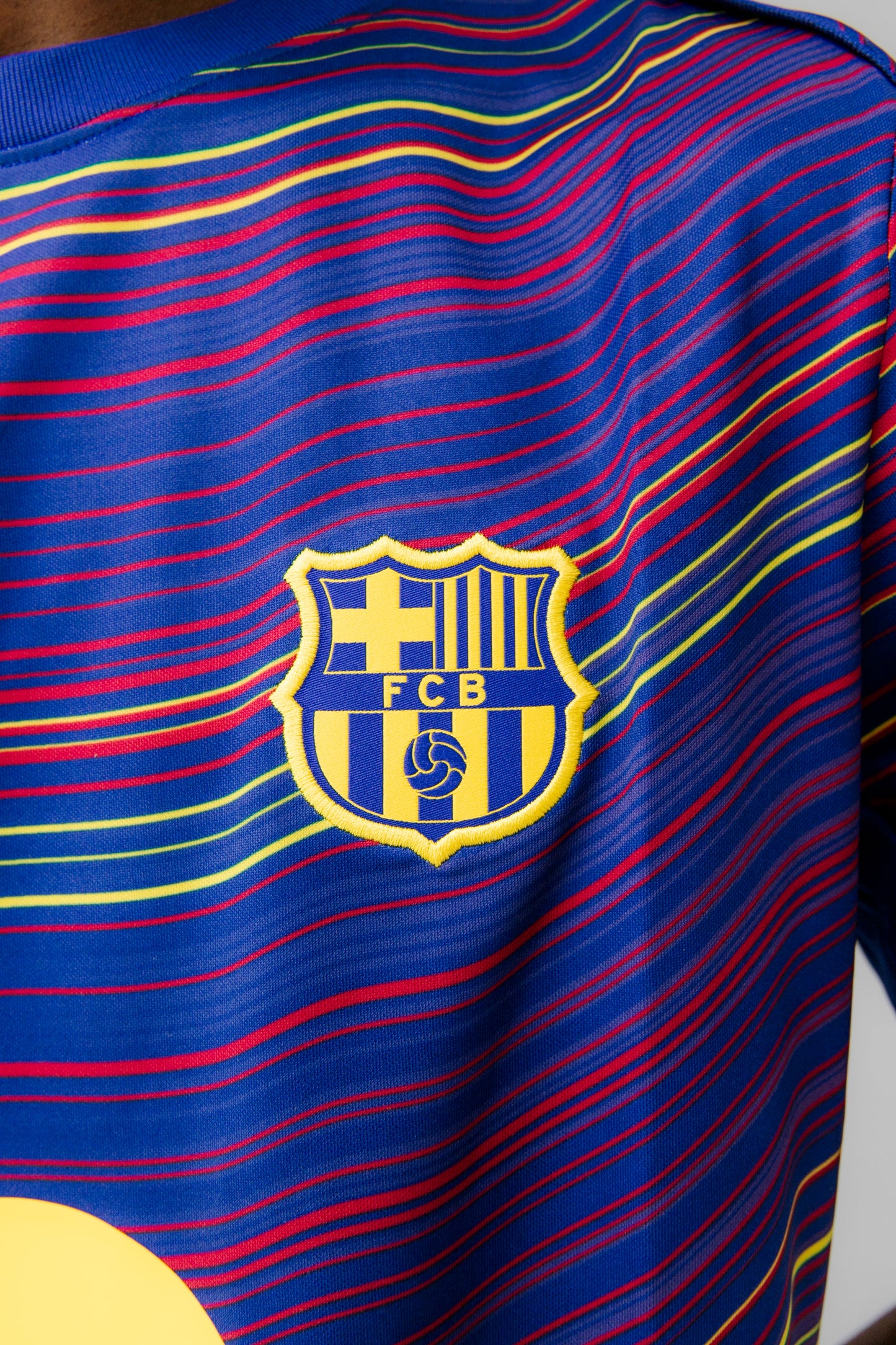 Person wearing FC Barcelona Pre-Match jersey featuring multicolored wave pattern, yellow Nike logo, club crest, and Spotify sponsor.
