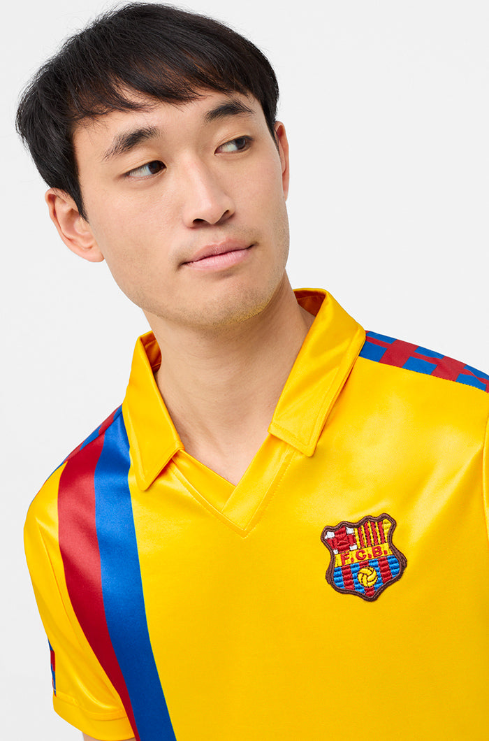 Yellow short-sleeve polo shirt with FC Barcelona crest and vertical red and blue stripe design.