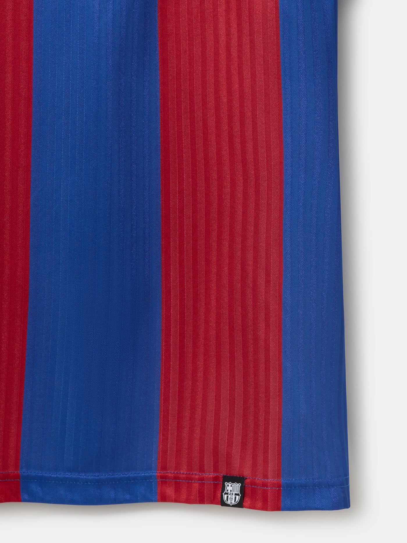 Man wearing a retro-style FC Barcelona jersey with wide vertical red and blue stripes, featuring the club's crest on the left chest and a classic V-neck collar design.
