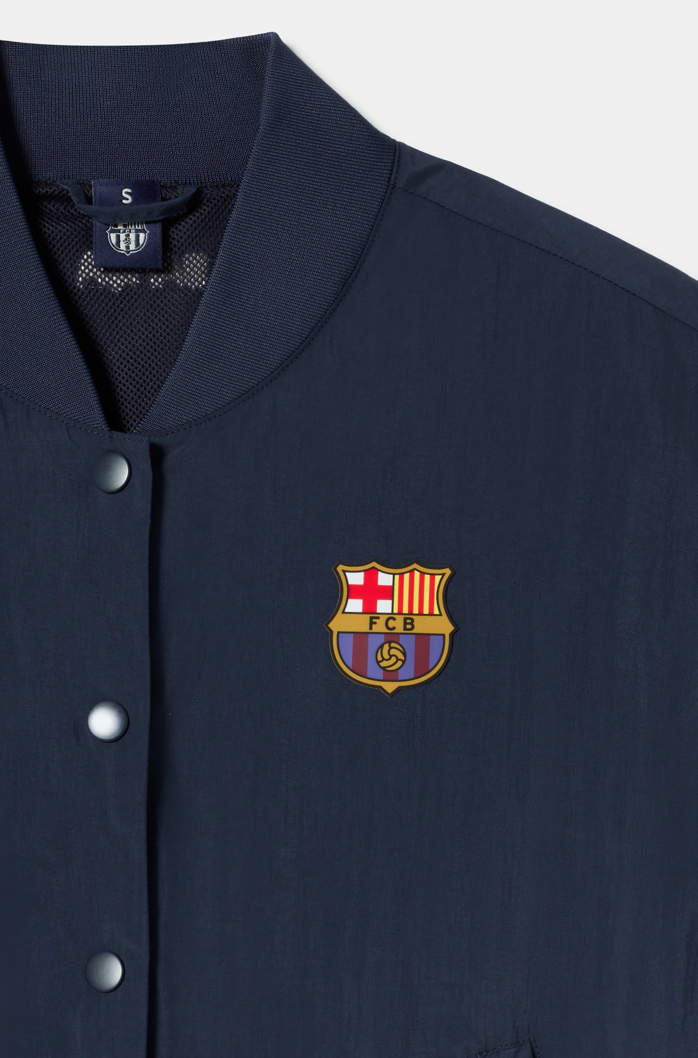 Navy blue FC Barcelona bomber jacket with red bands on the sleeves. The jacket features the club crest on the left chest and the year "1899" on the right chest, with a front snap button closure and ribbed cuffs and hem.