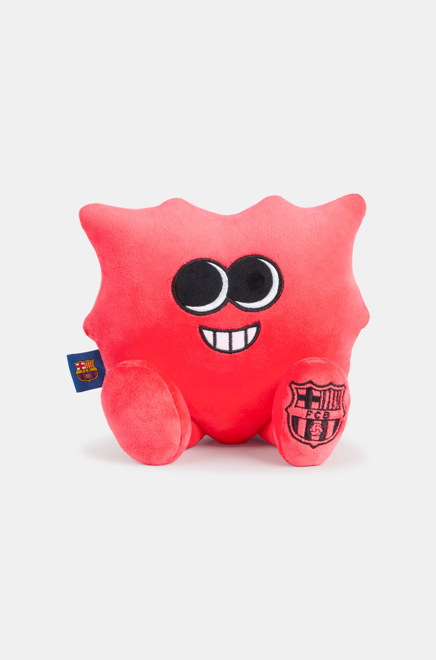 Red plush toy with a smiling face, featuring the FC Barcelona crest on one foot and a club tag on the side