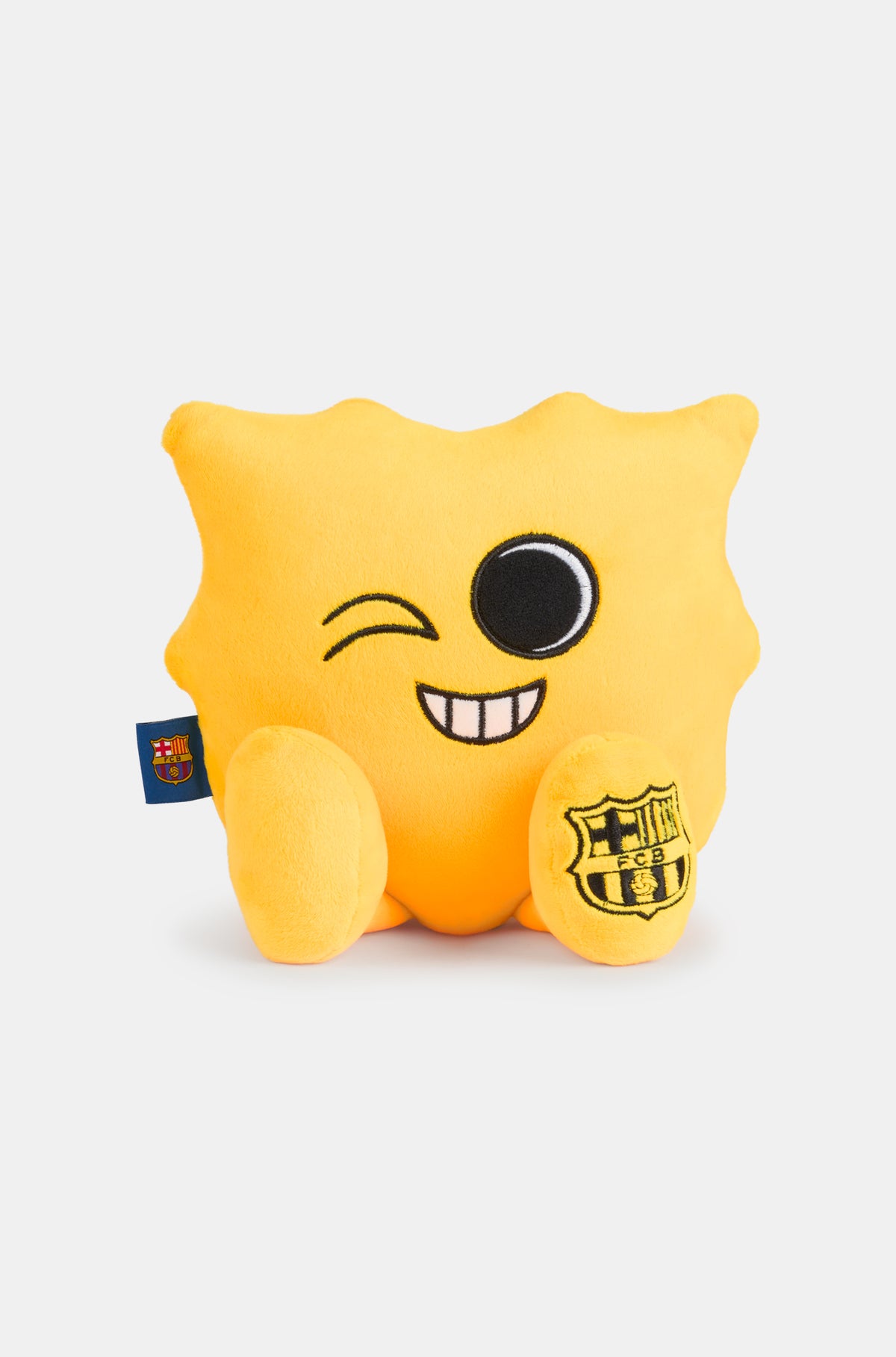 Yellow plush toy with a winking face and a wide smile, featuring the FC Barcelona crest on one foot and a club tag on the side