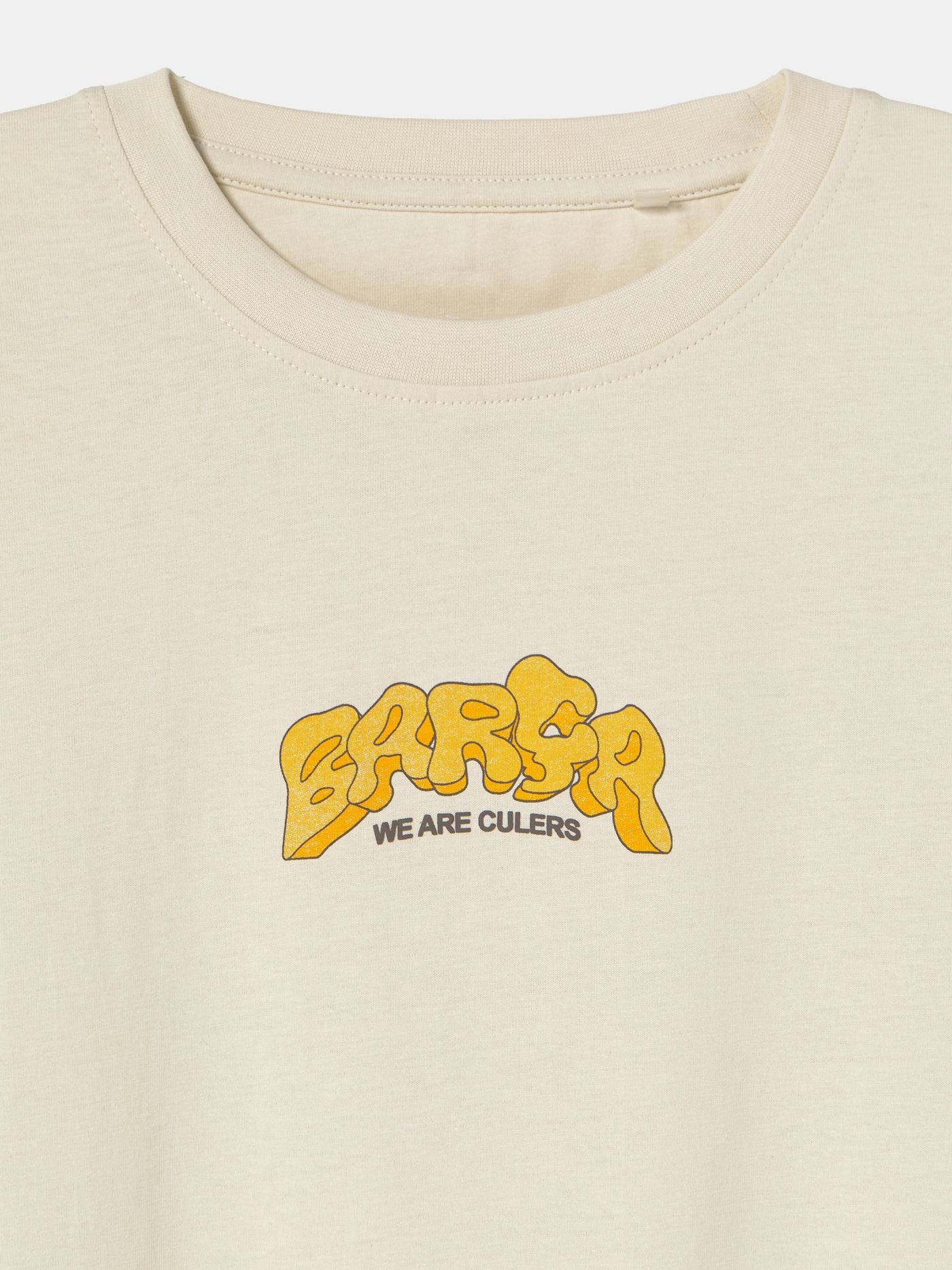 Beige FC Barcelona T-shirt featuring a vibrant vintage-style back print with the word "Barça" in large retro bubble letters. The graphic includes a football, flags, and stadium elements in bold colors within a shield-like frame. A ribbon below the design reads “Since 1899” and “Més que un club.”