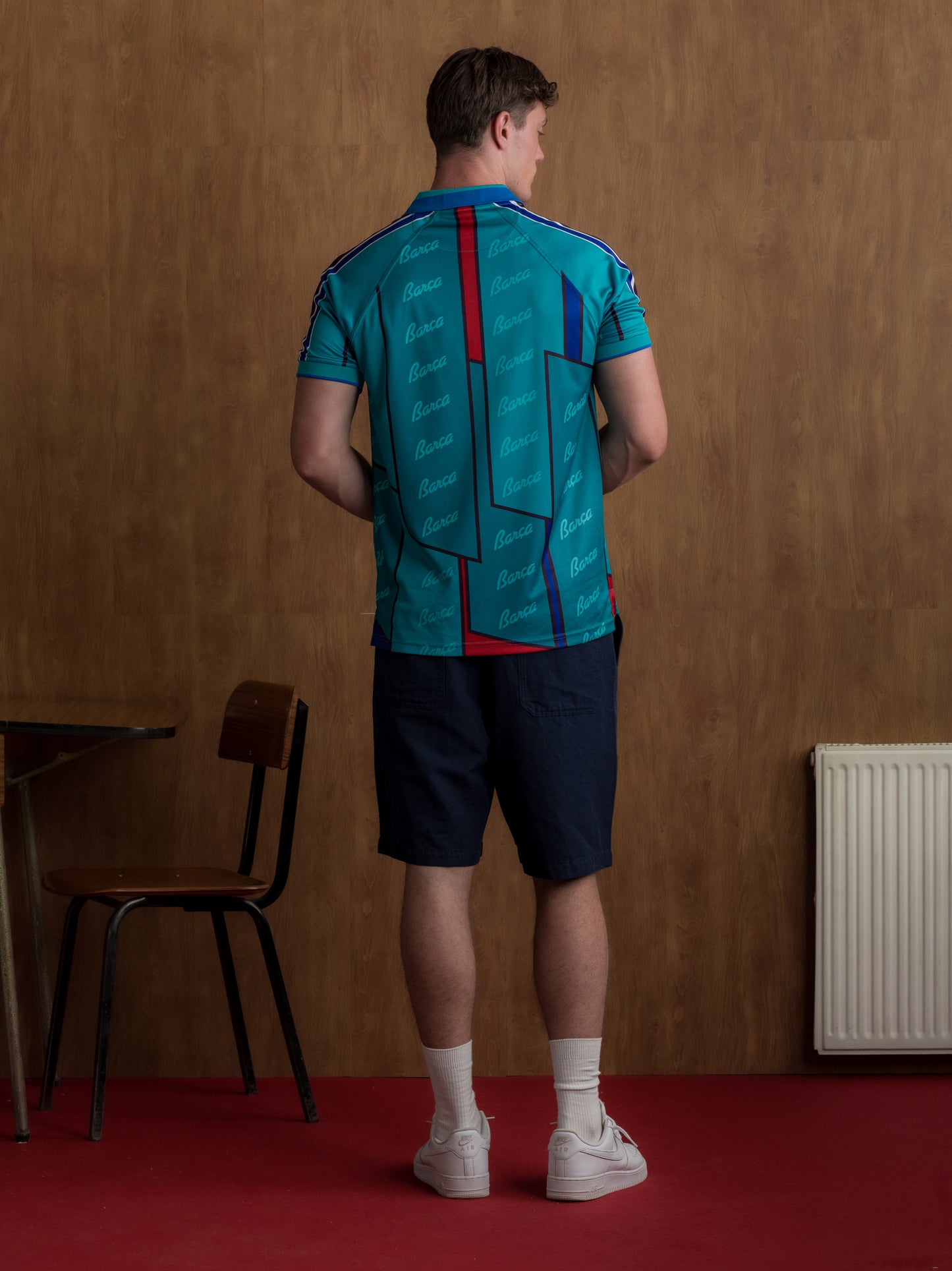 Teal short-sleeve polo shirt with FC Barcelona crest, blue and red accents, and Barça-themed script print.