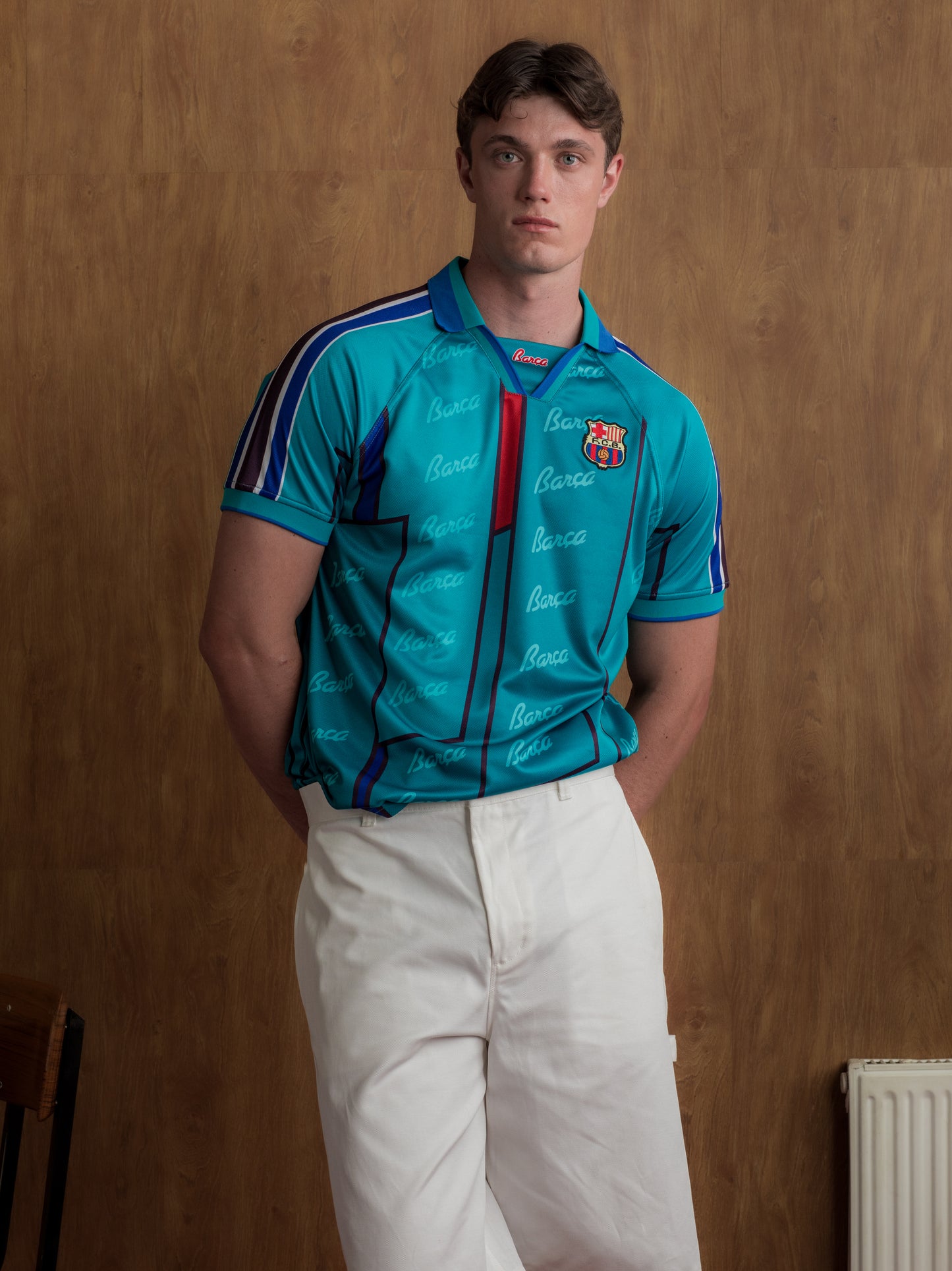Teal short-sleeve polo shirt with FC Barcelona crest, blue and red accents, and Barça-themed script print.