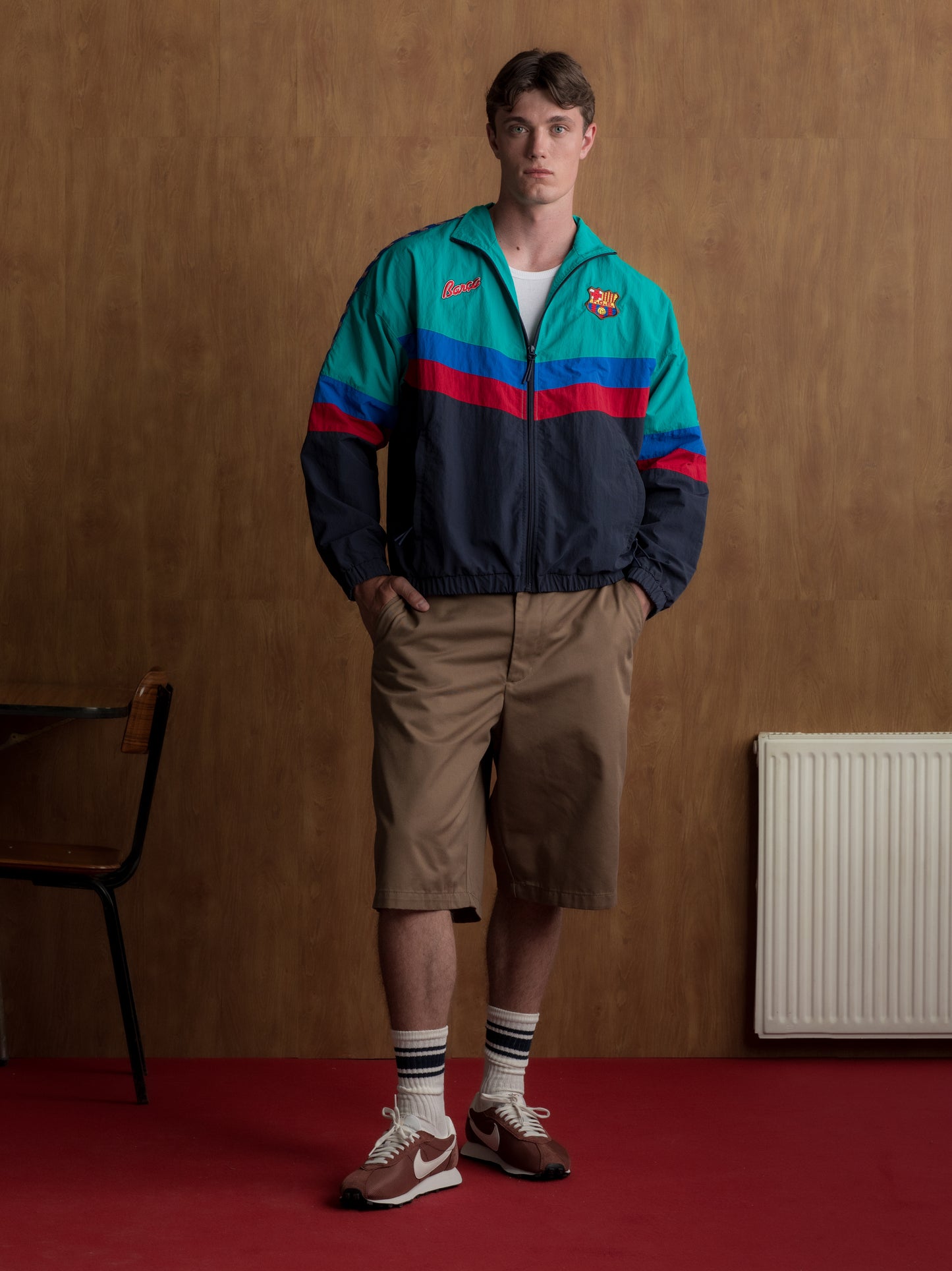 Retro-style windbreaker in teal, red, blue, and navy with FC Barcelona crest and embroidered 'Barça' text on the chest.