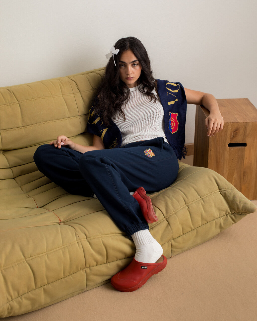 Model wearing navy blue FC Barcelona sweatpants with embroidered crest, paired with a white crop top and a navy scarf with gold lettering