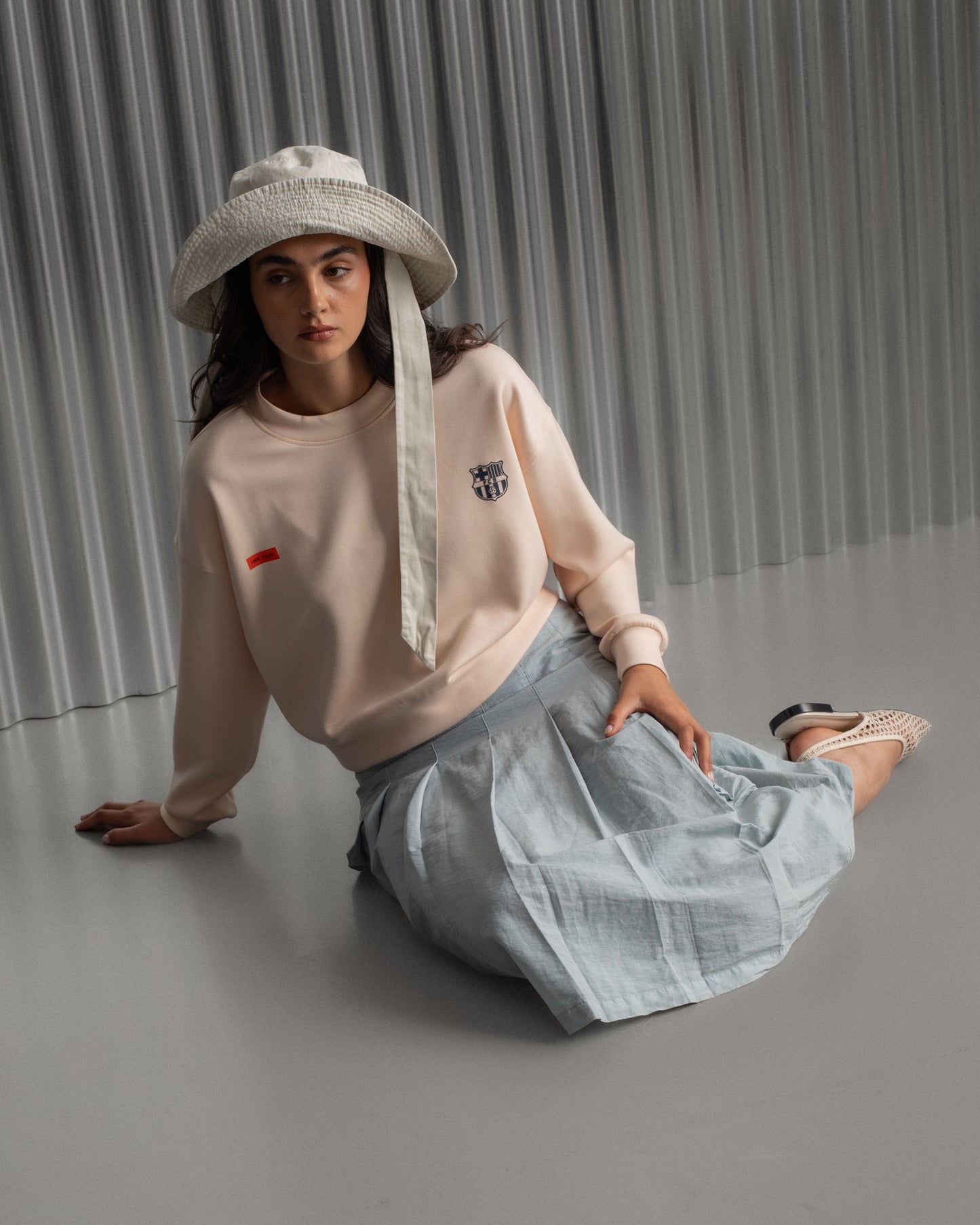 Light pink FC Barcelona sweatshirt with navy club crest on the chest and a small red rectangular detail on the left side.