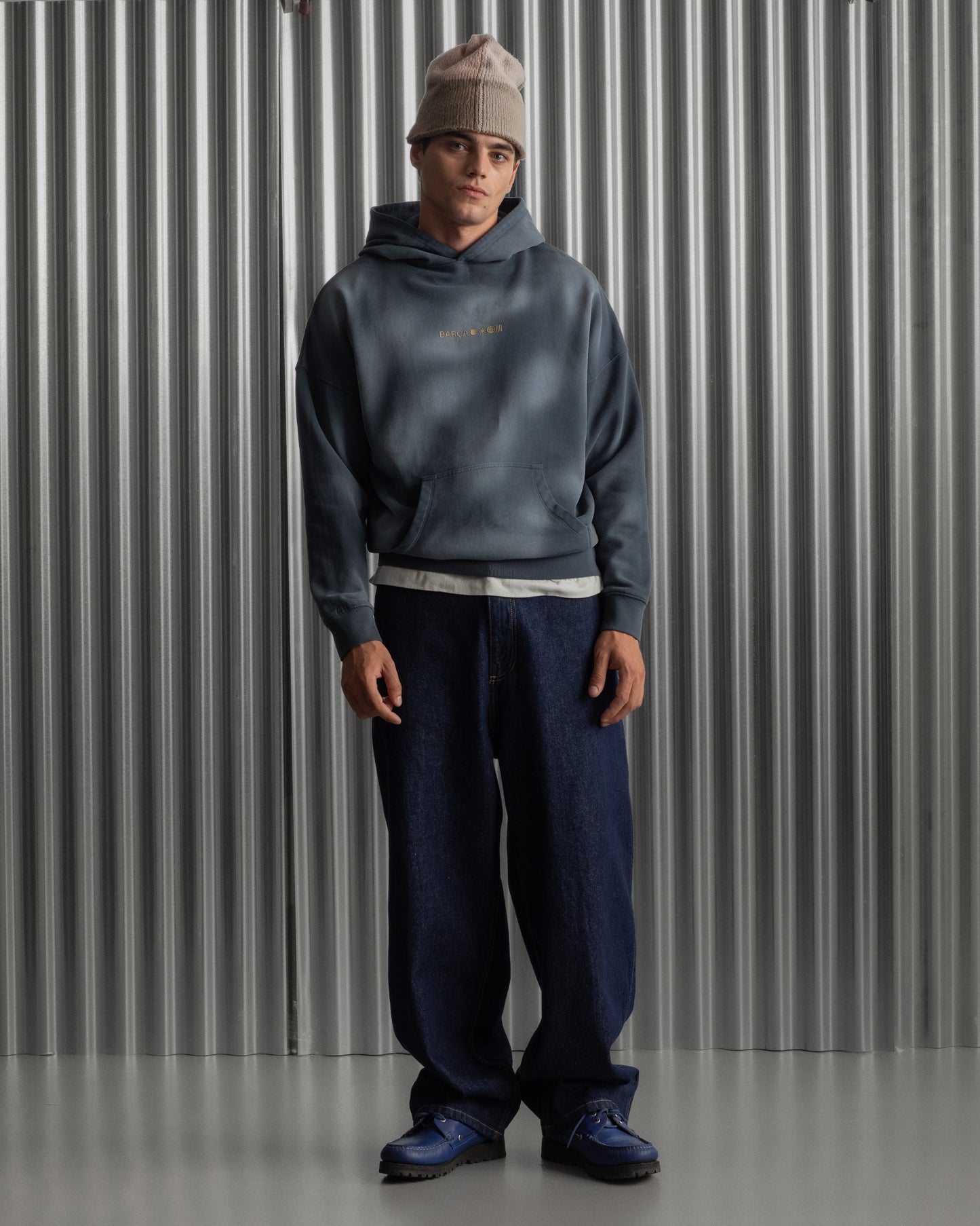 Man wearing a dark blue FC Barcelona hoodie with golden minimalist 'Barça' symbols printed on the chest