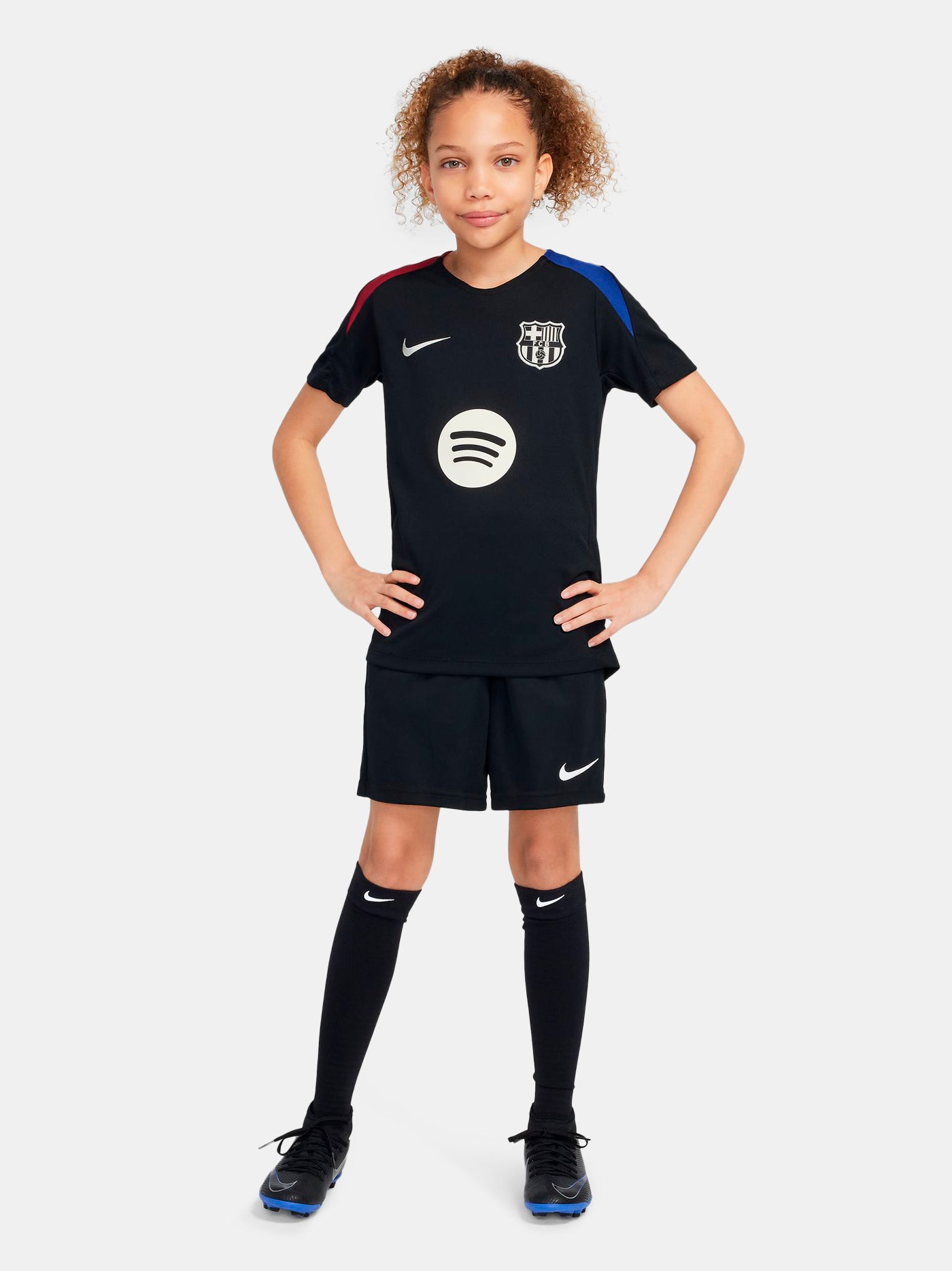 FC Barcelona black kids' training shirt with white Spotify logo and crest, red and blue shoulder details.