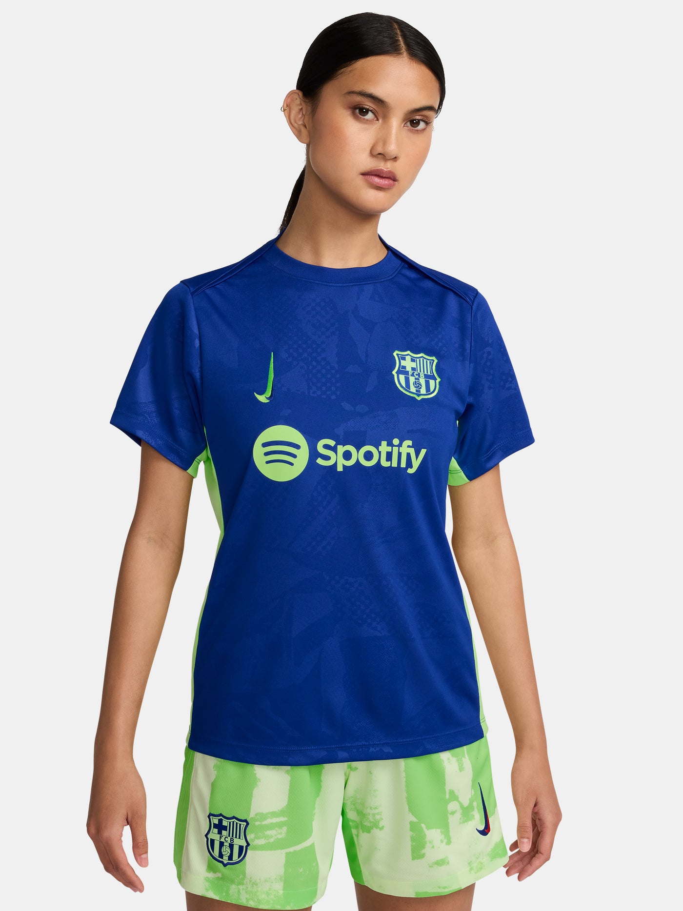 Women's FC Barcelona blue training jersey with neon green logos and side details.
