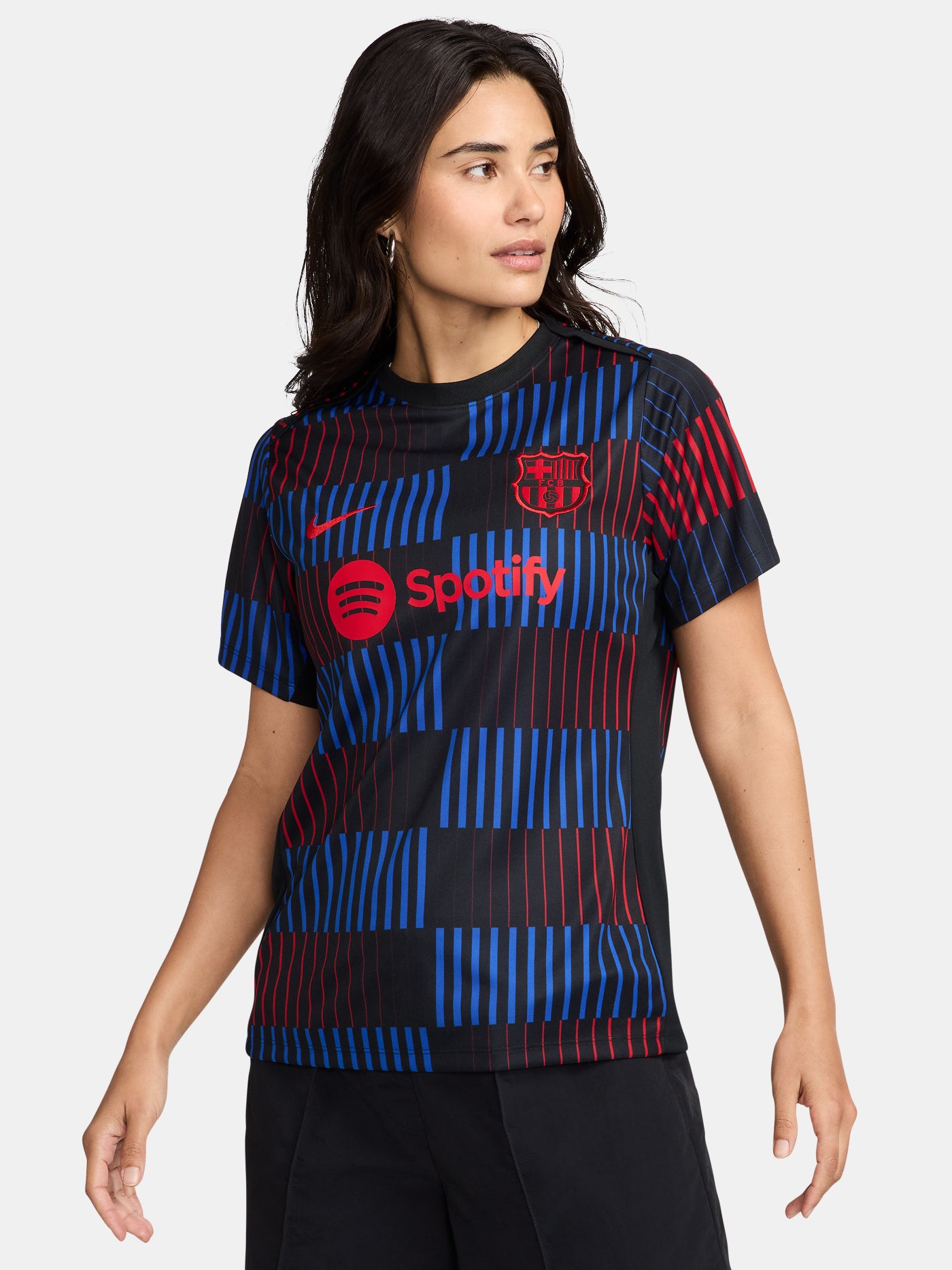 FC Barcelona warm-up shirt featuring a black base with a striking vertical stripe pattern in alternating red and blue. The shirt displays the red Spotify logo in the center, along with the Nike swoosh and FC Barcelona crest, also in red.