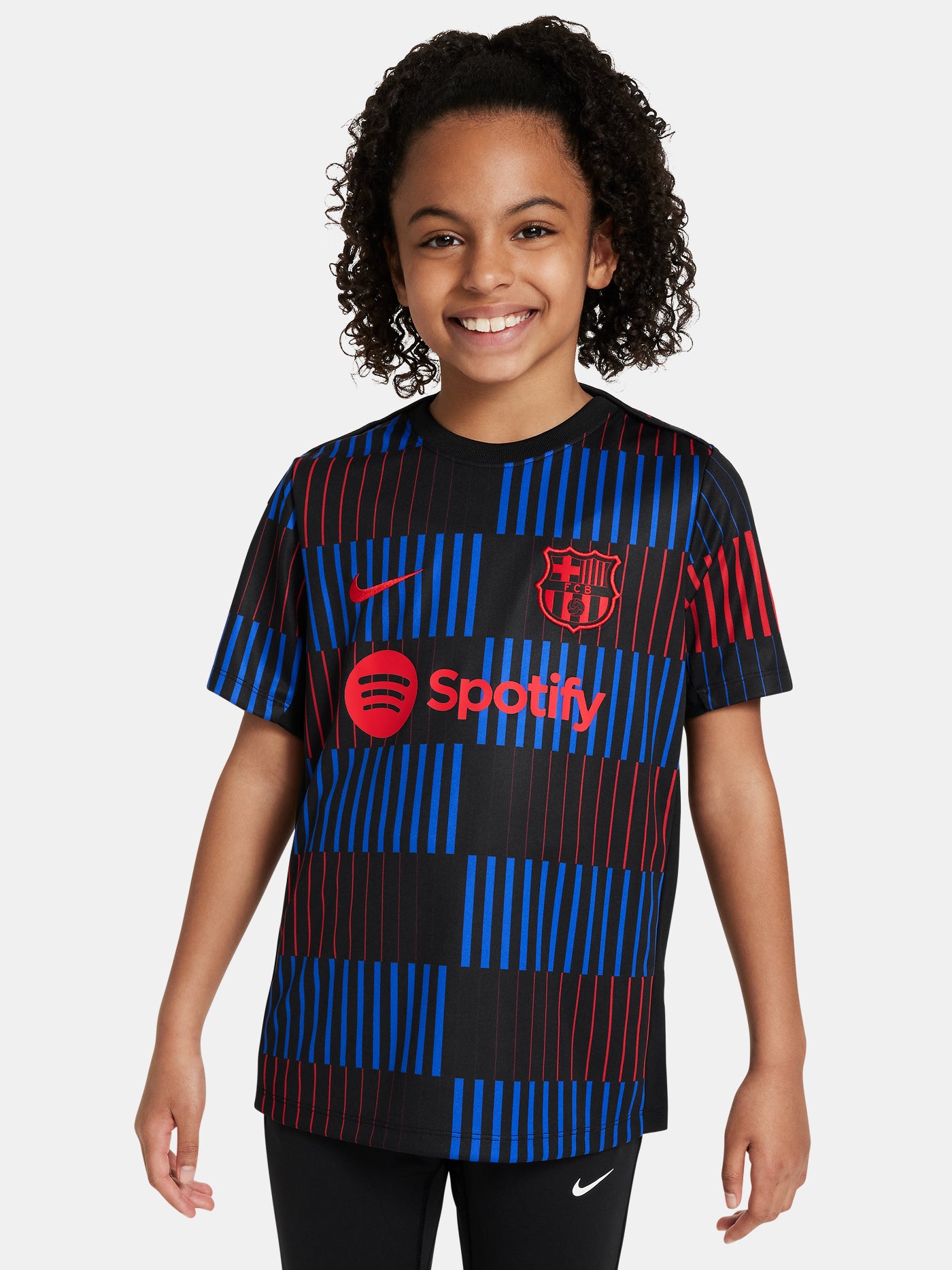 FC Barcelona warm-up shirt featuring a black base with a striking vertical stripe pattern in alternating red and blue. The shirt displays the red Spotify logo in the center, along with the Nike swoosh and FC Barcelona crest, also in red.