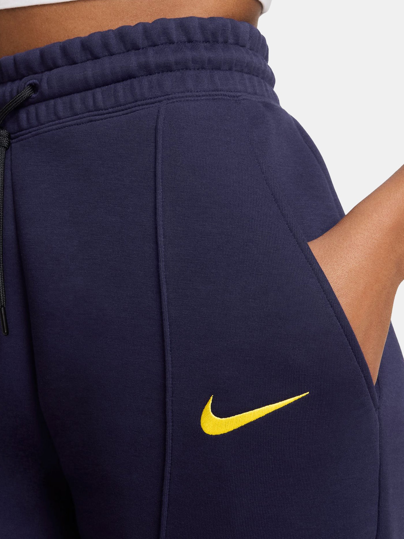 FC Barcelona women’s fleece joggers in navy blue. These pants feature a high-rise fit with an elastic drawstring waistband, ribbed cuffs, and front seams. The Barça crest and yellow Nike swoosh are placed on the front for a bold and sporty finish. Ideal for everyday comfort or casual training wear.