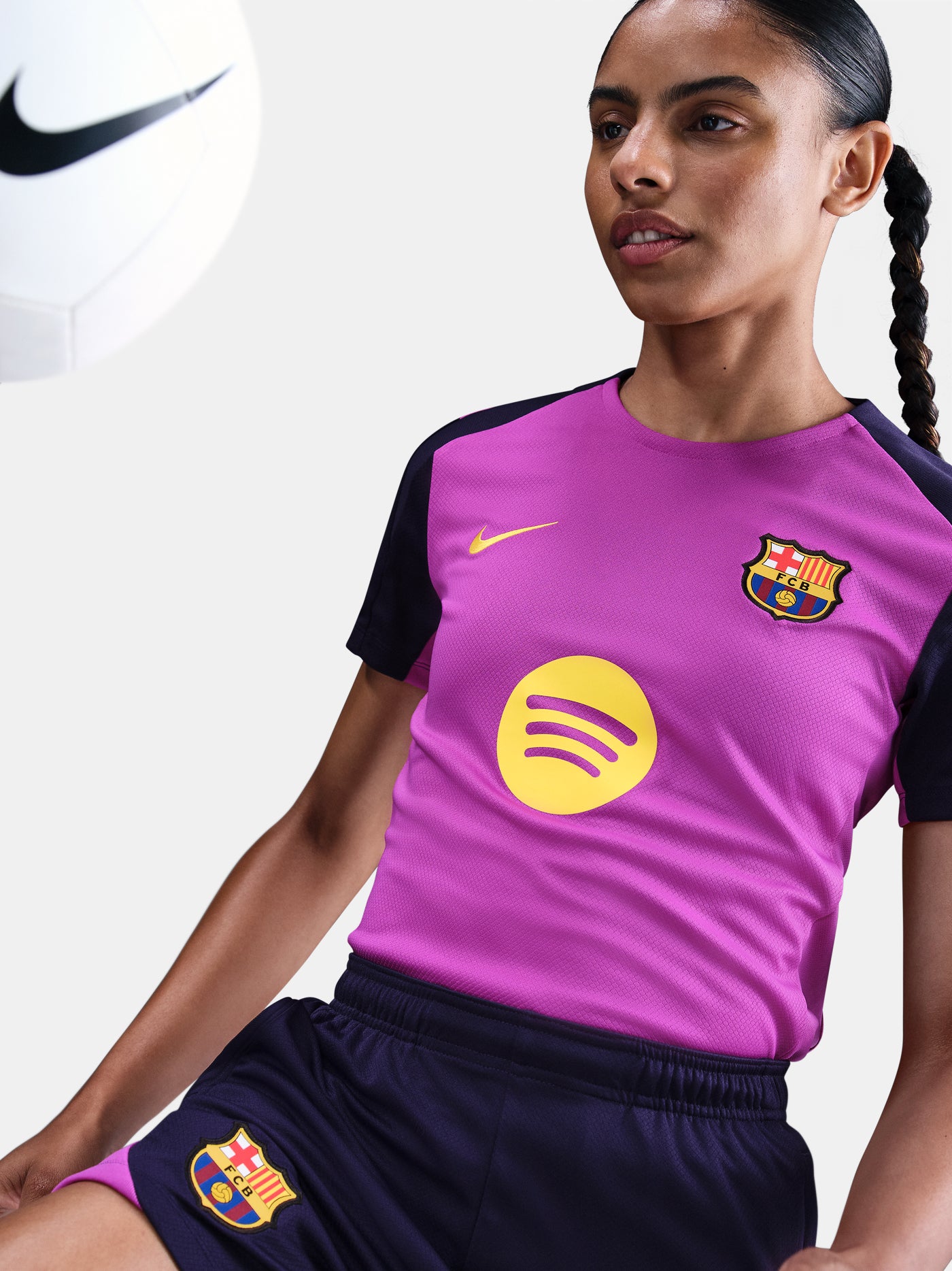Women's purple FC Barcelona training jersey with navy sleeves, yellow Nike logo, club crest, and Spotify sponsor on the front.