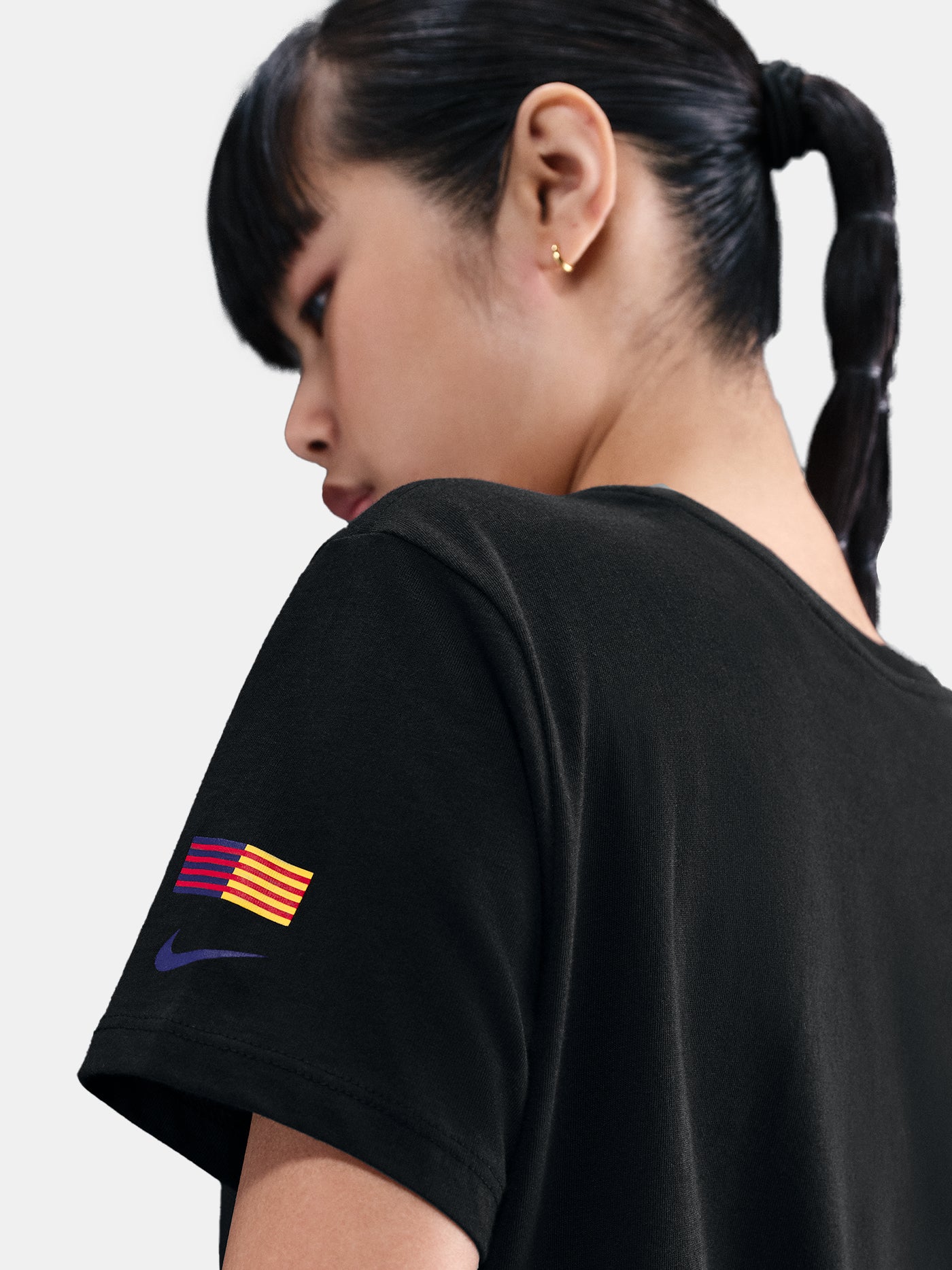 Black FC Barcelona Nike t-shirt with blue Barça crest on the chest, worn casually with blue pants and a black shoulder bag