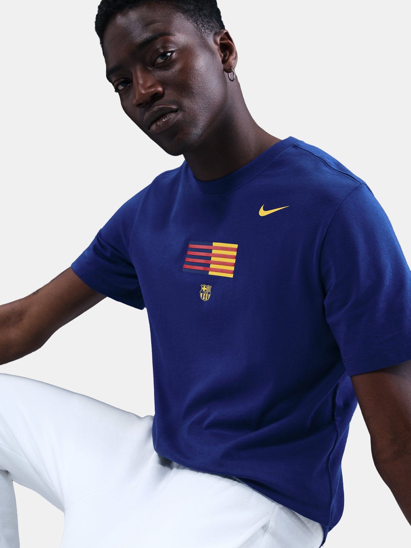 FC Barcelona men's t-shirt in royal blue featuring a minimalist front graphic with the Catalan and club colors, accompanied by the Nike Swoosh and Barça’s “Més que un club” symbol underneath. The design offers a clean and athletic streetwear look, perfect for everyday wear or matchday style.