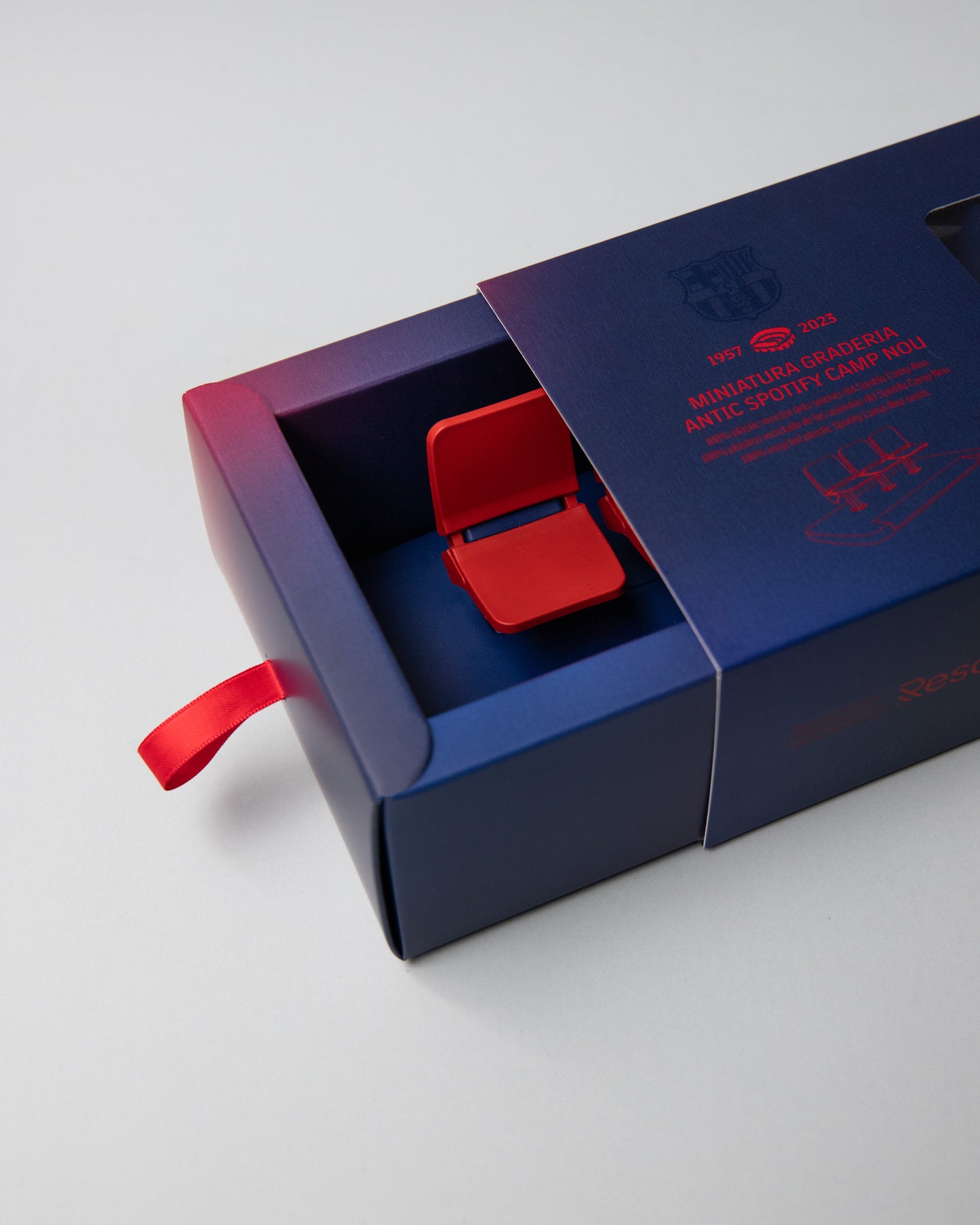 Miniature display of three iconic red Camp Nou stadium seats mounted on a blue base, commemorating the years 1957–2023, marking the historical timeline of FC Barcelona’s legendary stadium.