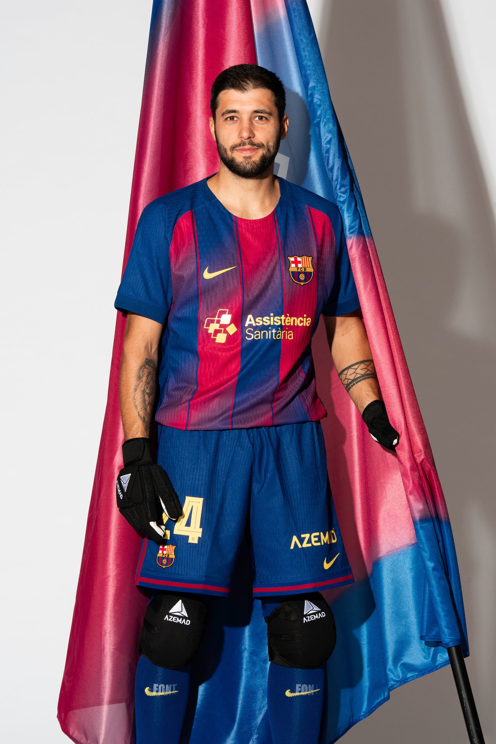 FC Barcelona roller hockey kit with red and blue vertical stripes, standing in front of a Barça flag