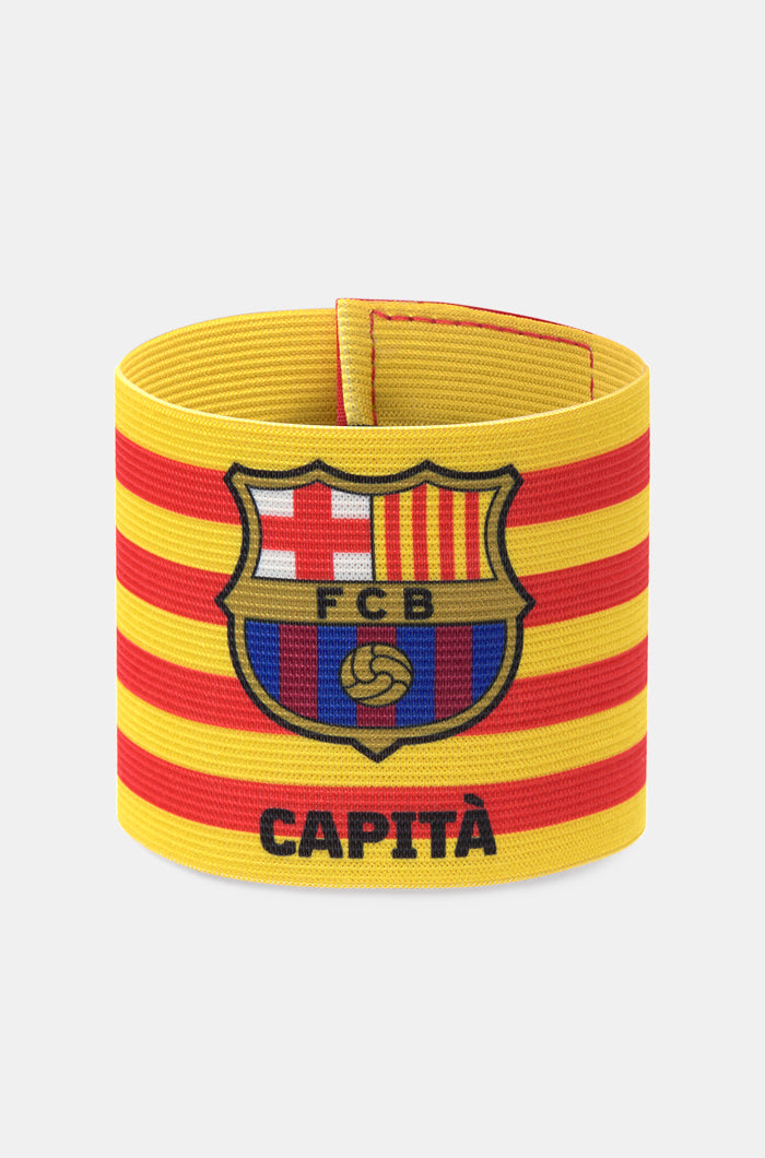 Yellow and red striped FC Barcelona captain's armband featuring the club crest and the word "CAPITÀ" printed in black.