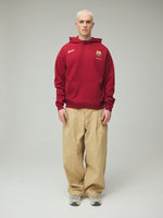 Model wearing a red FC Barcelona hoodie with crest in a lifestyle ecommerce image.
