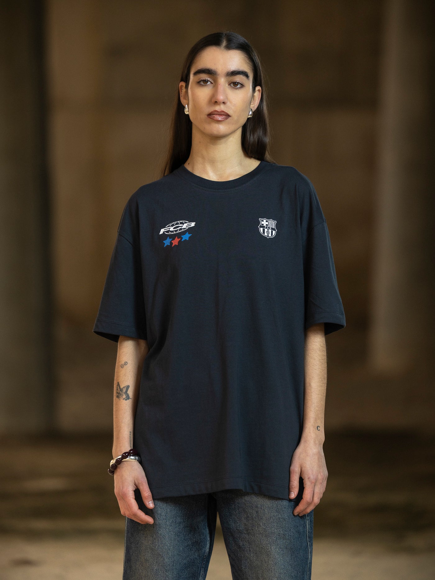 Person wearing a black t-shirt with logos on a dark background