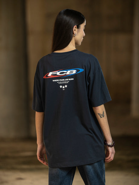 Person wearing a black t-shirt with a logo on the back against a brown background
