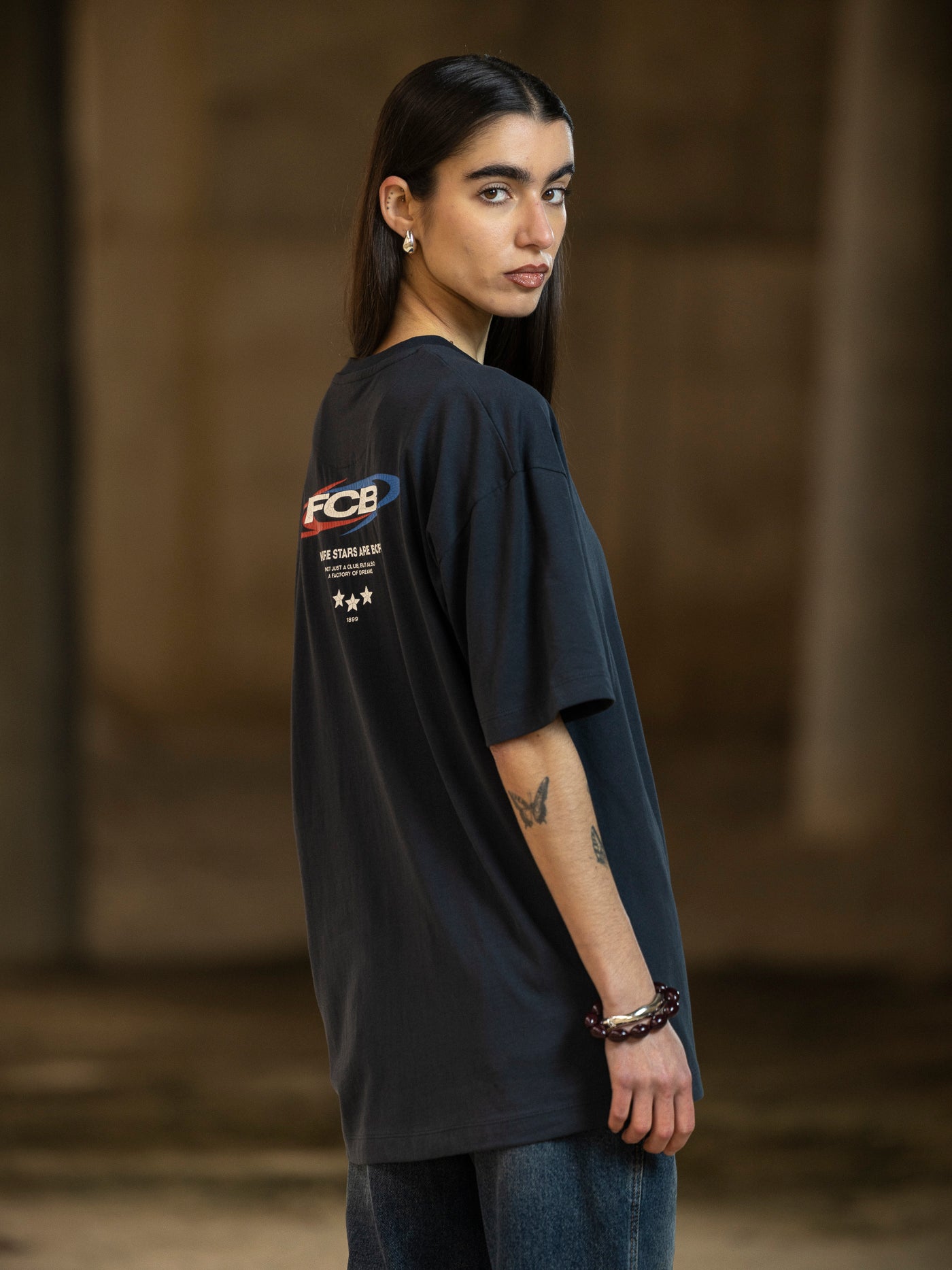 Person wearing a black t-shirt with a logo on the sleeve against a blurred background