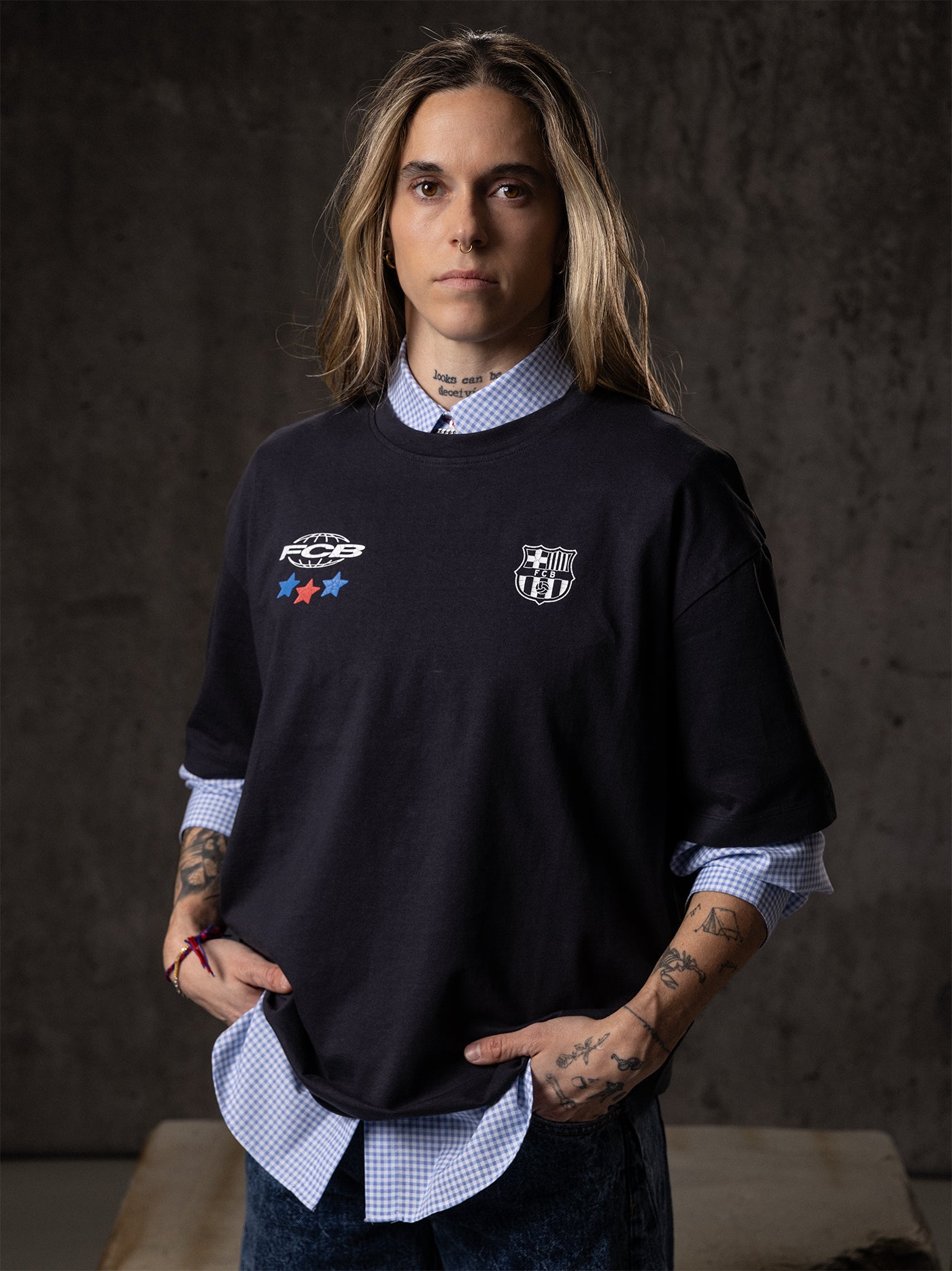 Person wearing a black sweater with logos against a dark background