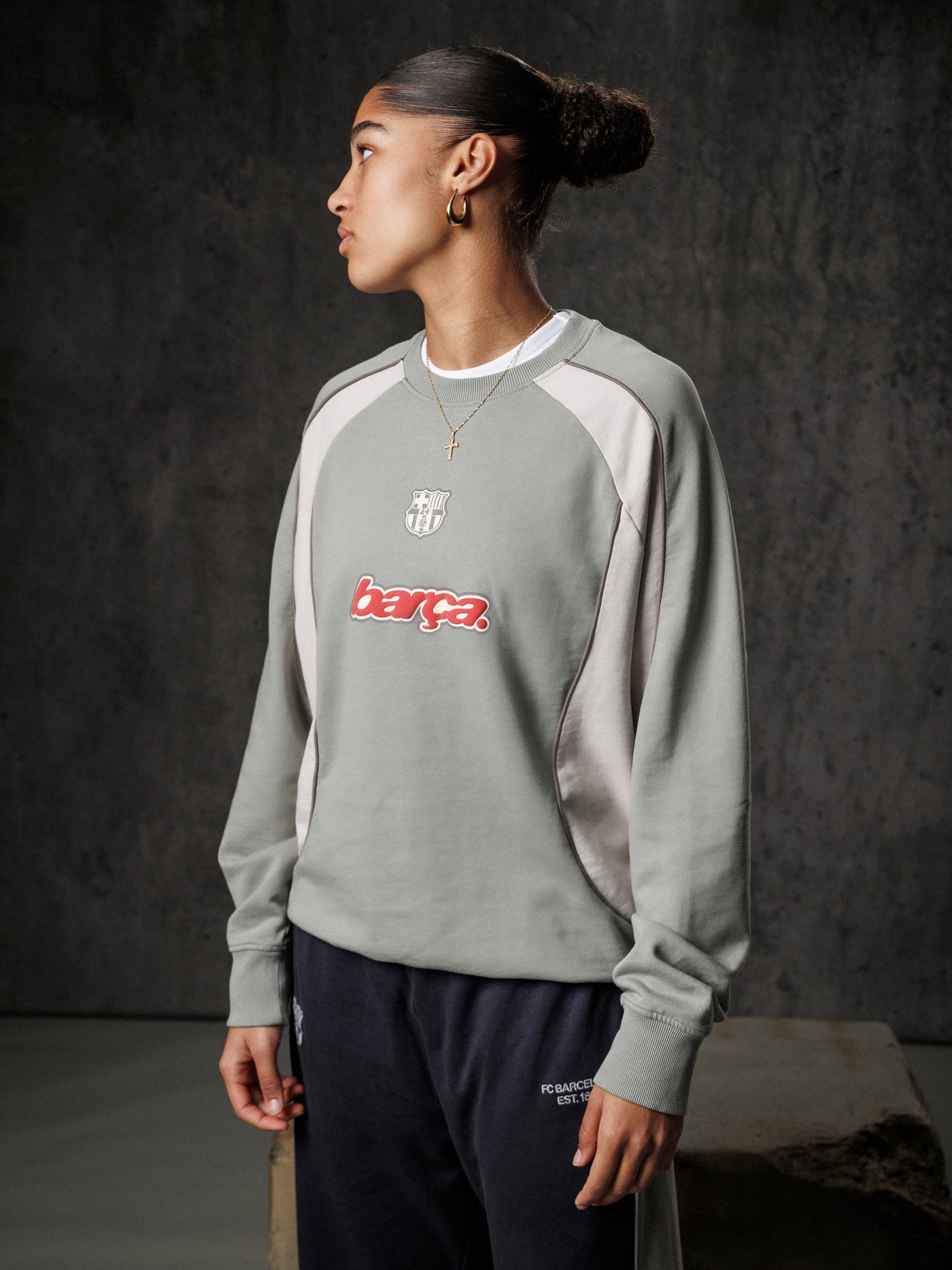 Person wearing a gray sweatshirt with 'barca' logo against a dark background
