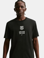 Person wearing a black t-shirt with a logo and text on a plain background