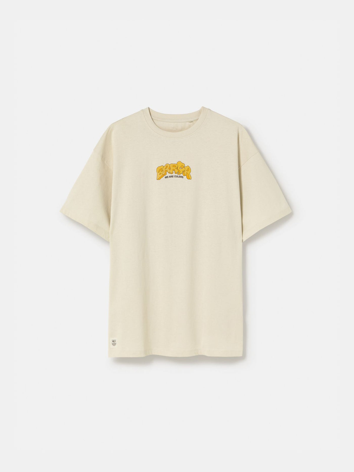 Beige FC Barcelona T-shirt featuring a vibrant vintage-style back print with the word "Barça" in large retro bubble letters. The graphic includes a football, flags, and stadium elements in bold colors within a shield-like frame. A ribbon below the design reads “Since 1899” and “Més que un club.”