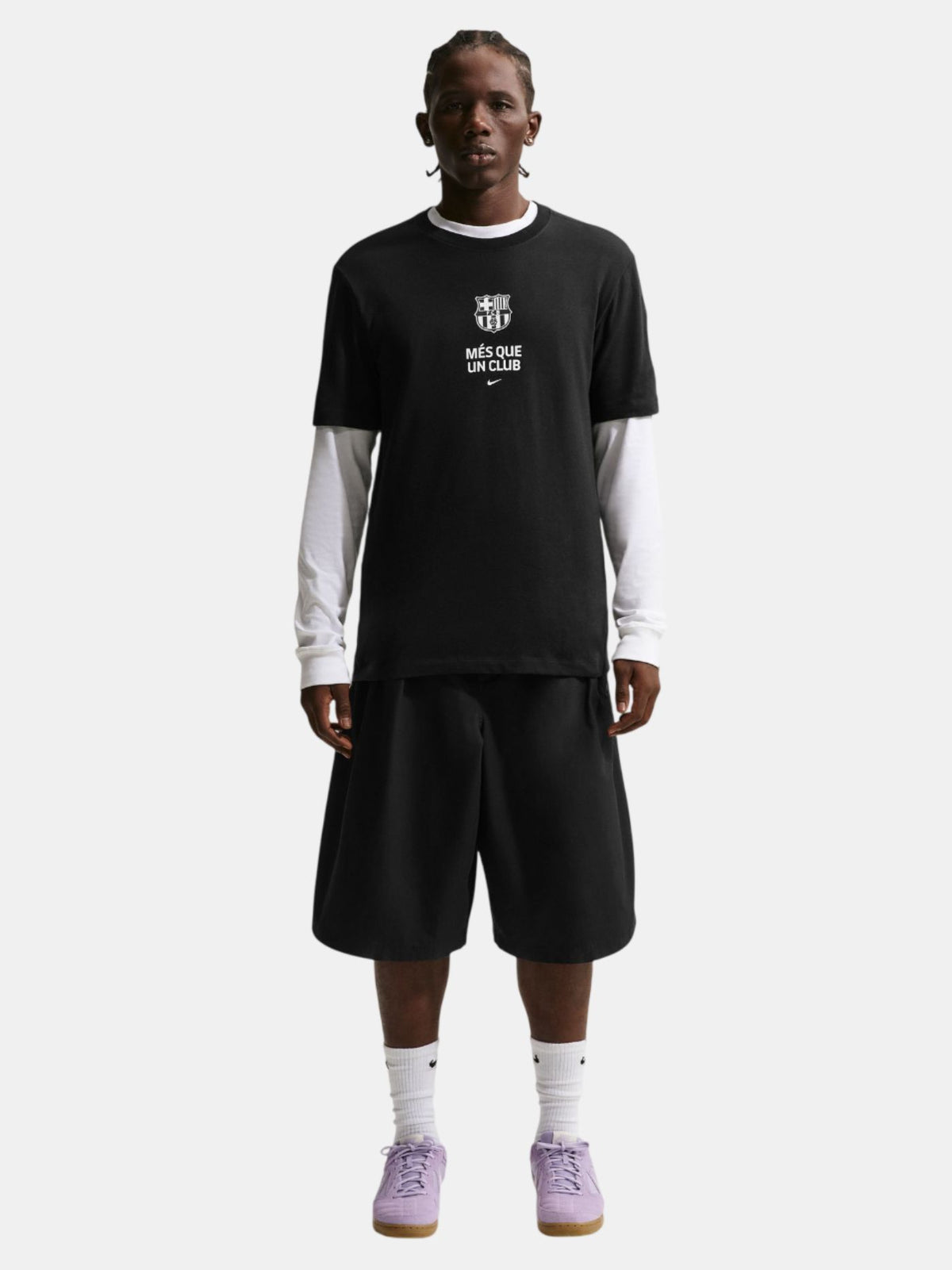 Person wearing a black t-shirt with text and black shorts on a white background