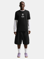 Person wearing a black t-shirt with text and black shorts on a white background