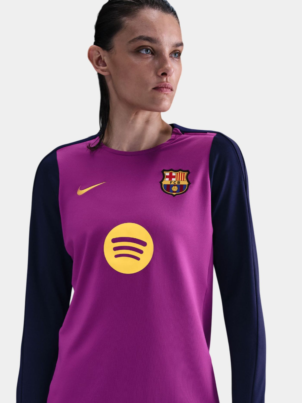 Woman wearing a FC Barcelona long-sleeve jersey in purple with navy sleeves, featuring the club crest, Nike logo, and Spotify sponsor in yellow.