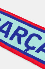 Light blue FC Barcelona scarf with red and blue borders, featuring the word 'BARÇA' in dark blue and the club crest at both ends.