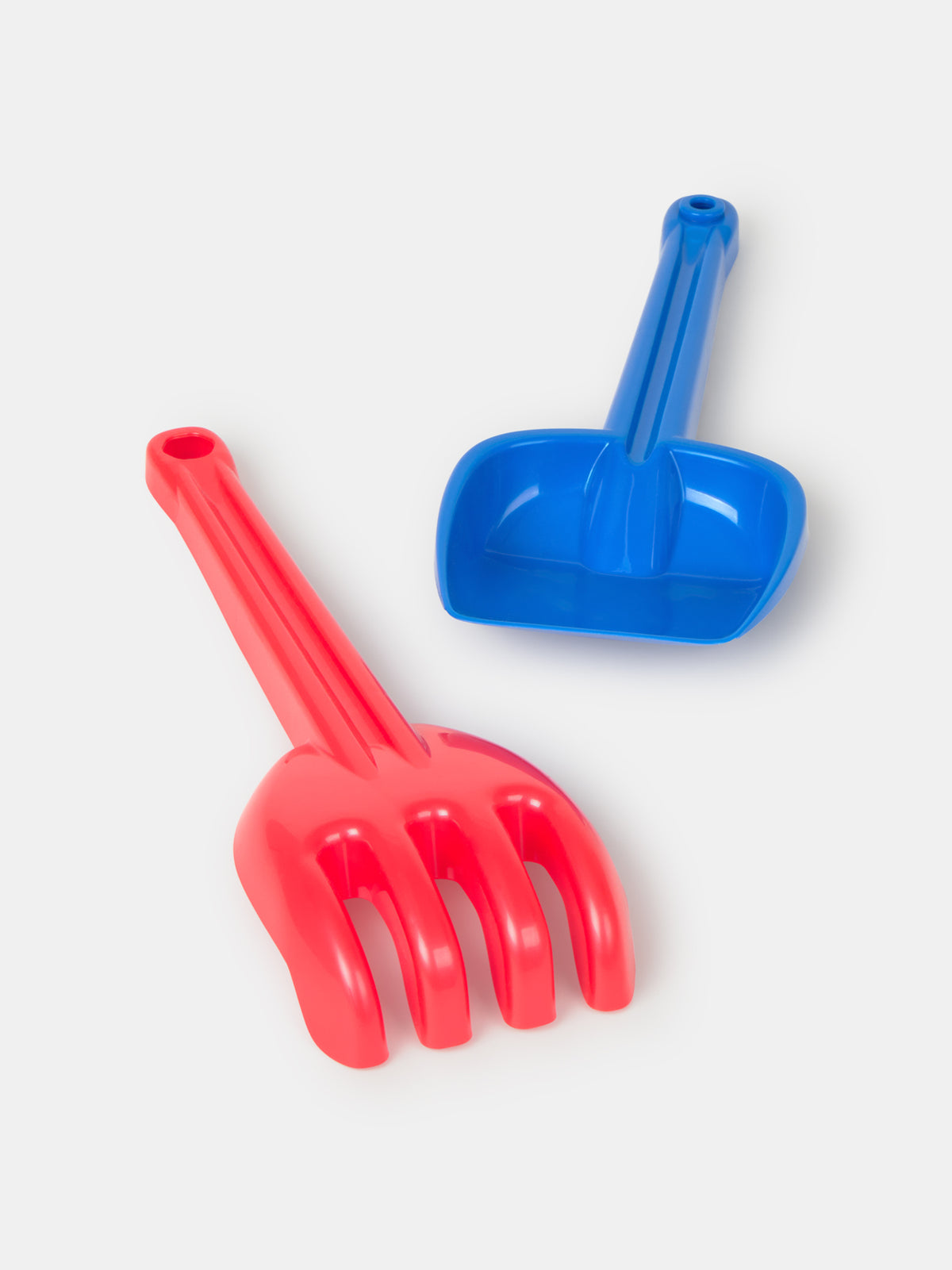 Red plastic rake and blue plastic shovel set for sand play.