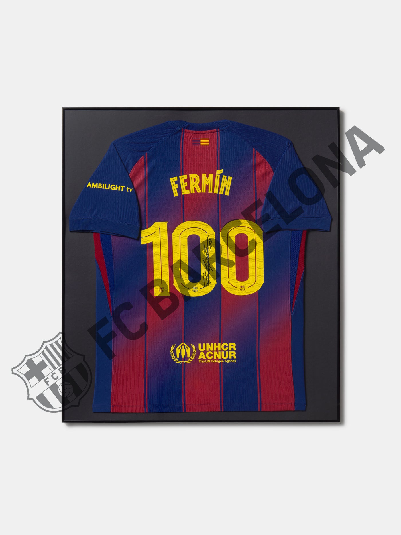 Camiseta del FC Barcelona enmarcada con el nombre Fermín y número 100 en la espalda, diseño azul y grana con detalles en amarillo y logotipo UNHCR ACNUR.