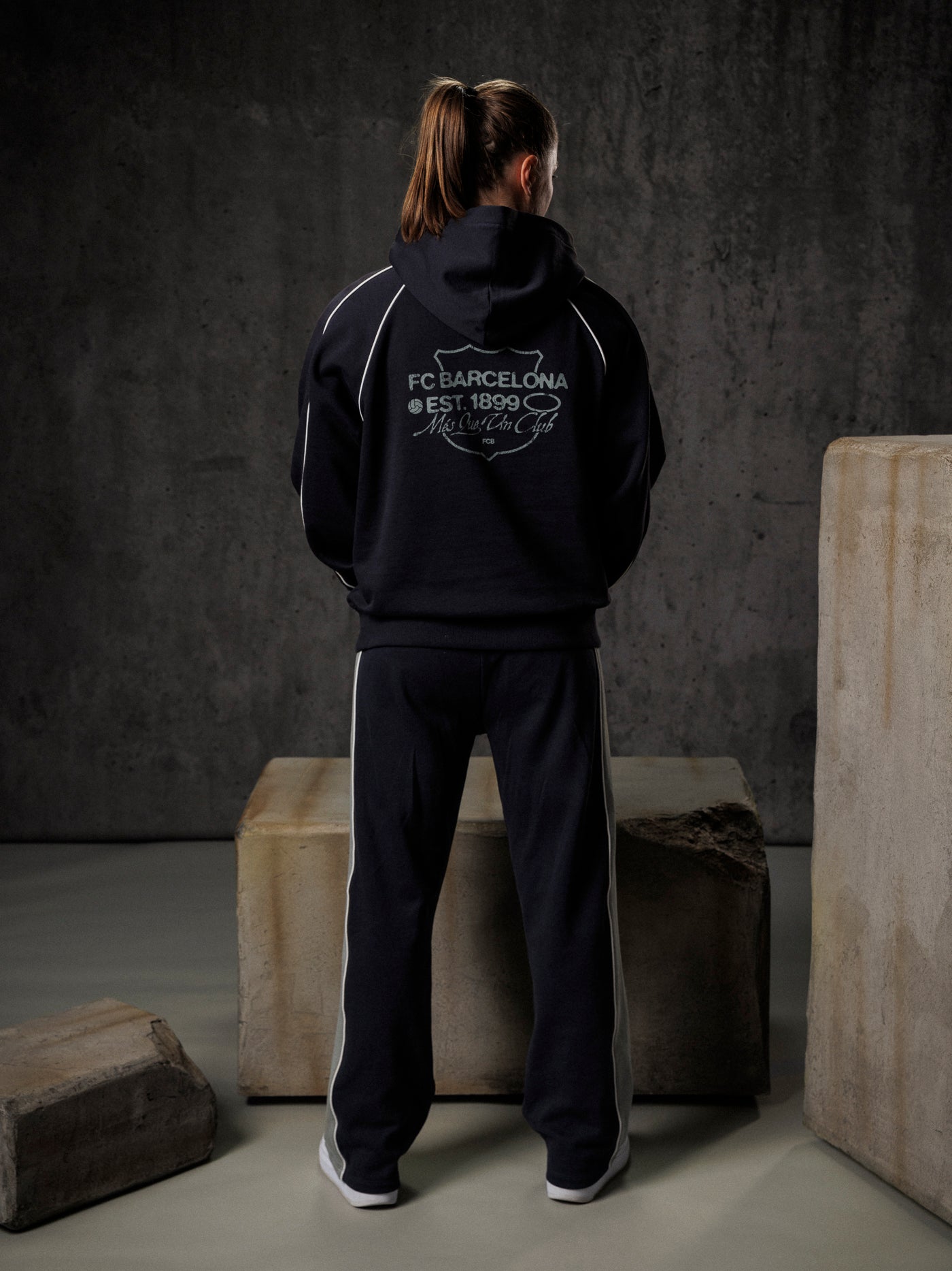 Person wearing a black hoodie with branding in an industrial setting