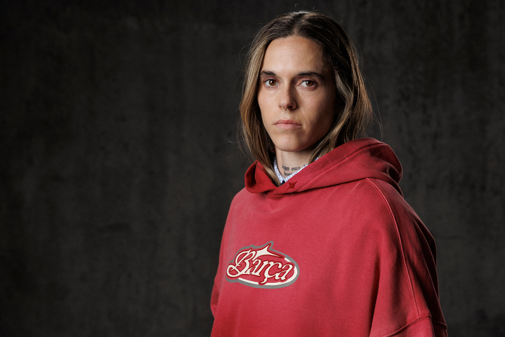 Person wearing a red hoodie with a logo on a dark background