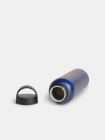 Bouteille bleue FC Barcelona montrée à côté de son bouchon à vis noir sur fond blanc.