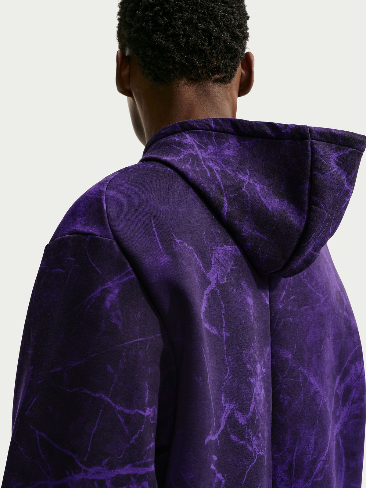Vista trasera de un modelo con sudadera con capucha morada jaspeada, capucha grande y mangas holgadas.