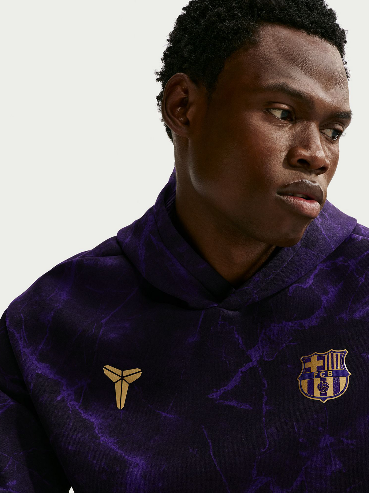 Modelo con sudadera morada con estampado marmolado, escudo del FC Barcelona y logo dorado en el pecho.