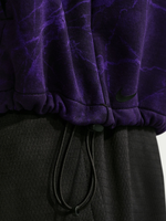 Primer plano del bajo de la sudadera con capucha morada de FC Barcelona, con un swoosh negro de Nike sobre un short negro con cordón.