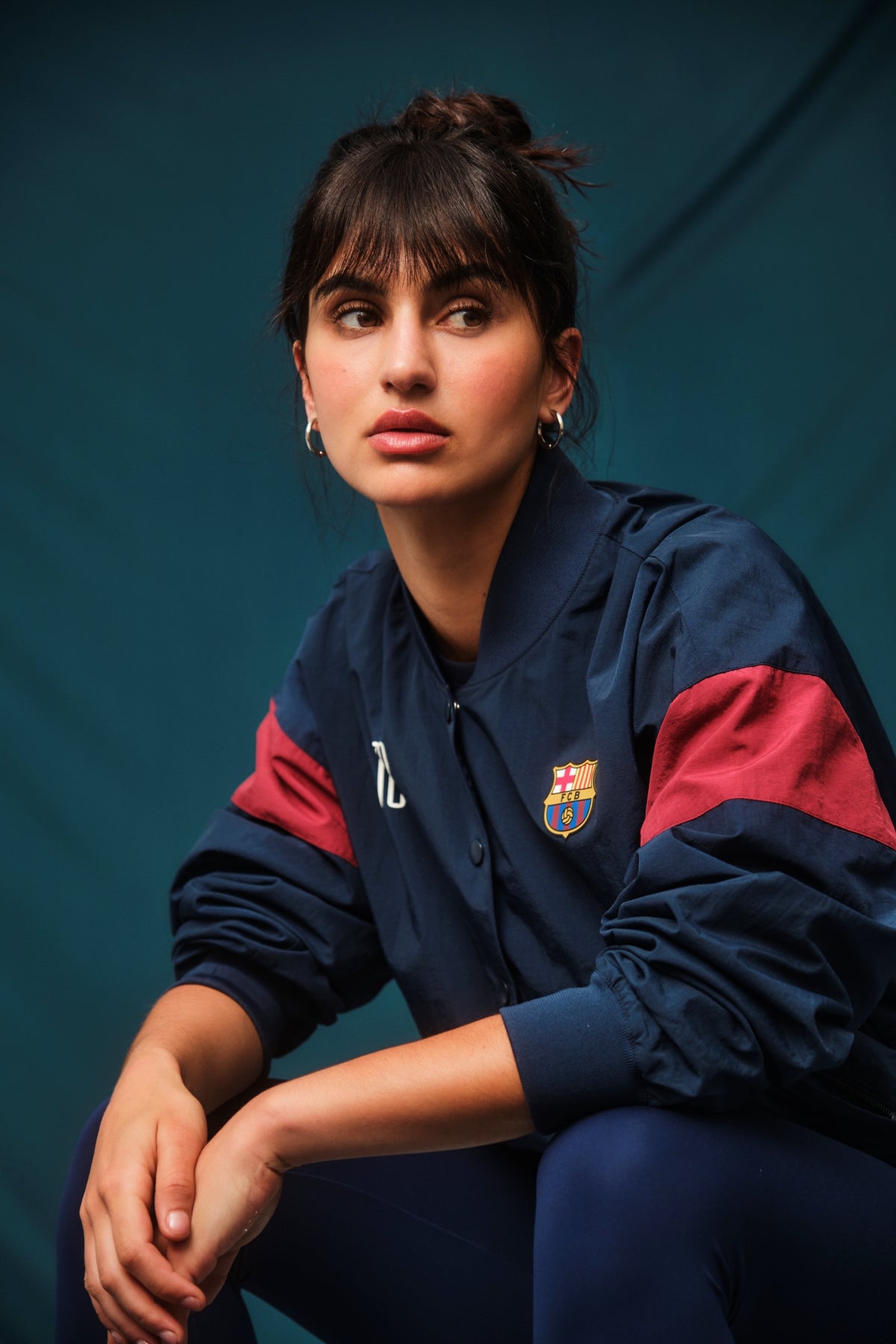 Navy blue FC Barcelona bomber jacket with red bands on the sleeves. The jacket features the club crest on the left chest and the year "1899" on the right chest, with a front snap button closure and ribbed cuffs and hem.