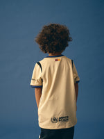 FC Barcelona kids' away kit set including beige jersey with black and purple details, black shorts with purple accents, and matching black socks, featuring club crest, Nike logo, Spotify sponsor, and Kobe Bryant tribute emblem.