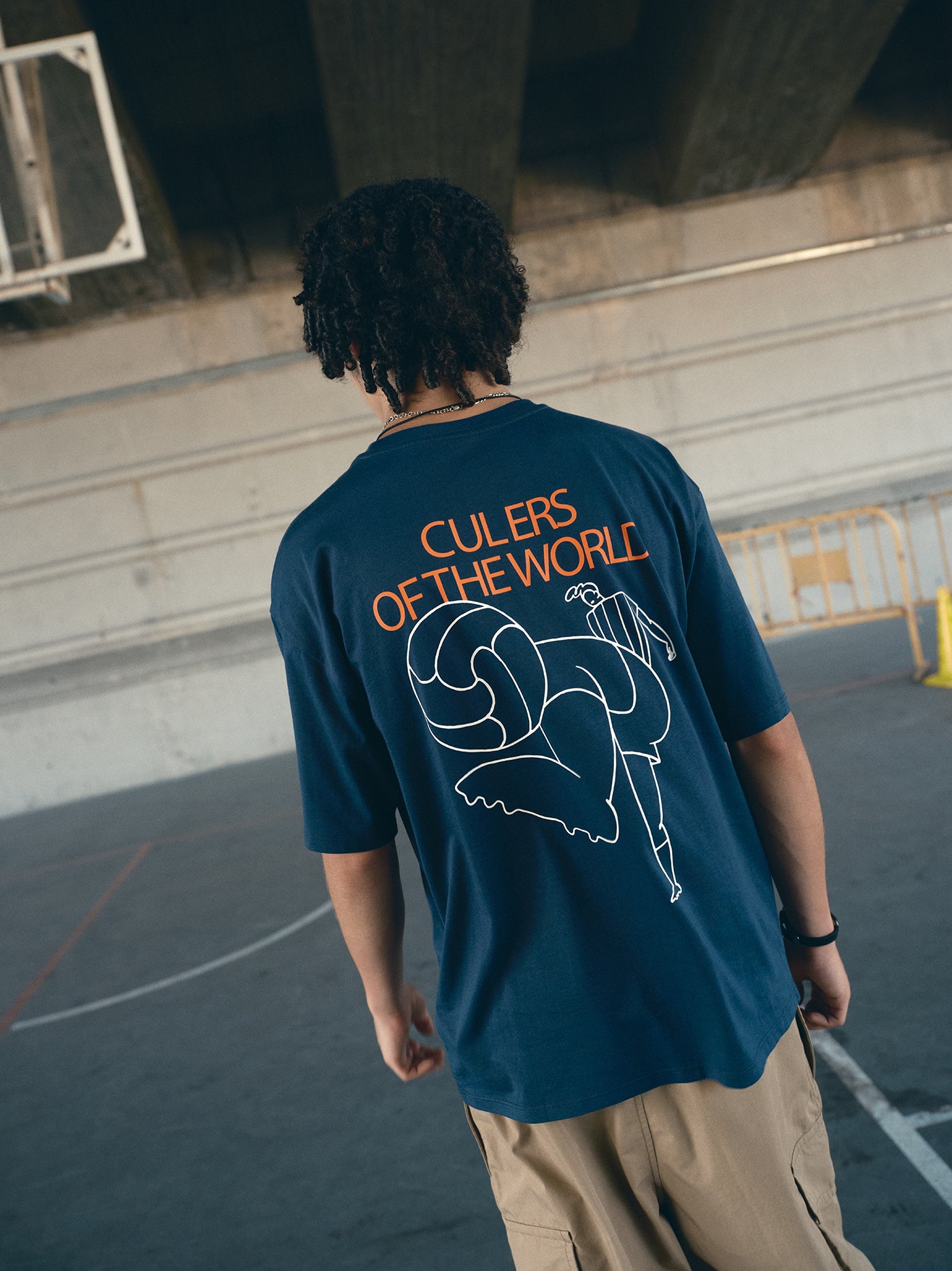 navy blue FC Barcelona t-shirt with the text 'CULERS OF THE WORLD' in orange and a white line illustration of a footballer kicking a ball.