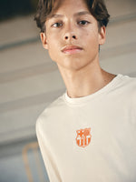 beige and orange gradient FC Barcelona t-shirt with 'EST. 1899' printed in bold orange text.