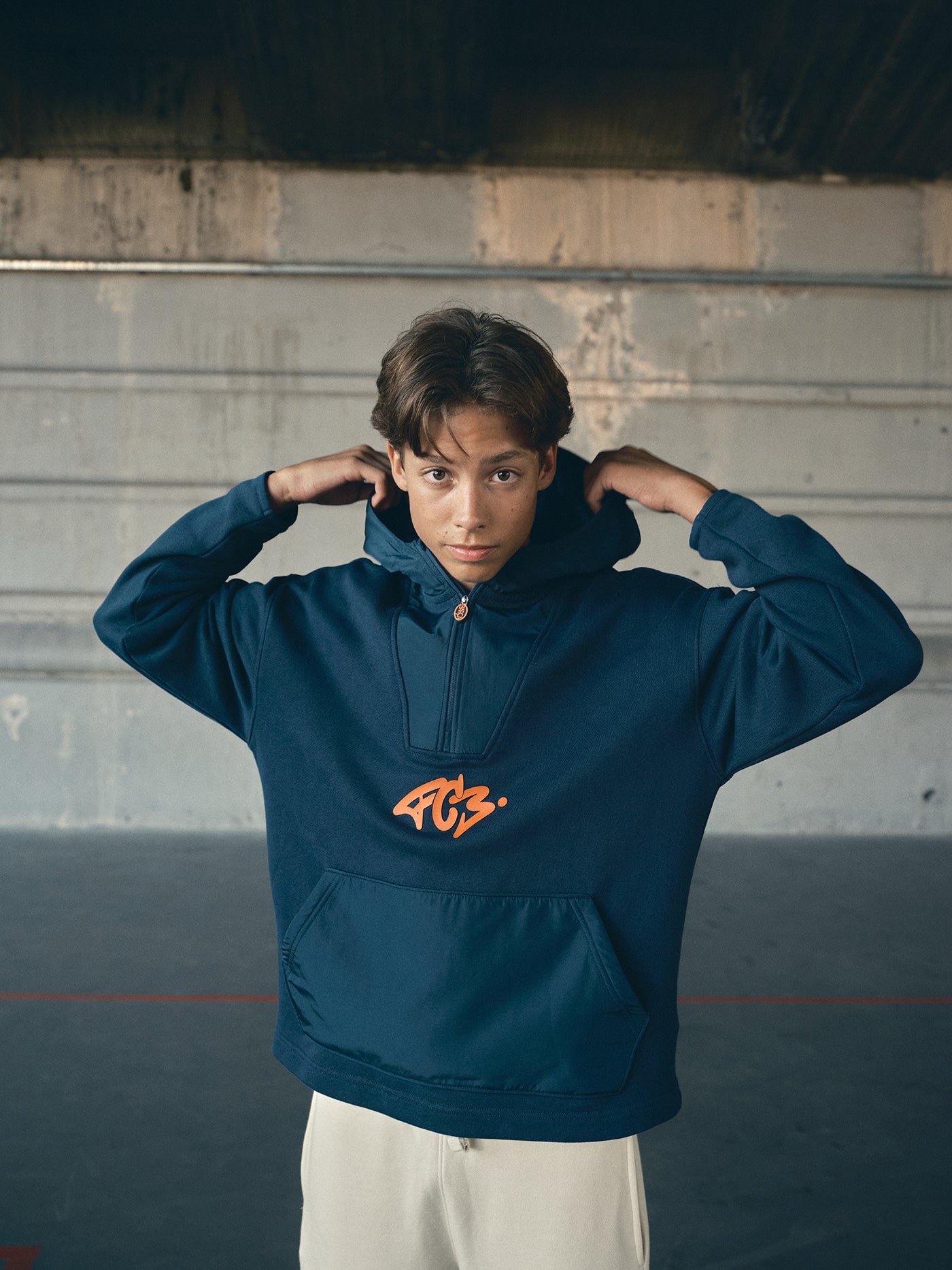 navy blue FC Barcelona hoodie featuring a front zipper and an orange graffiti-style 'FCB' logo printed on the chest