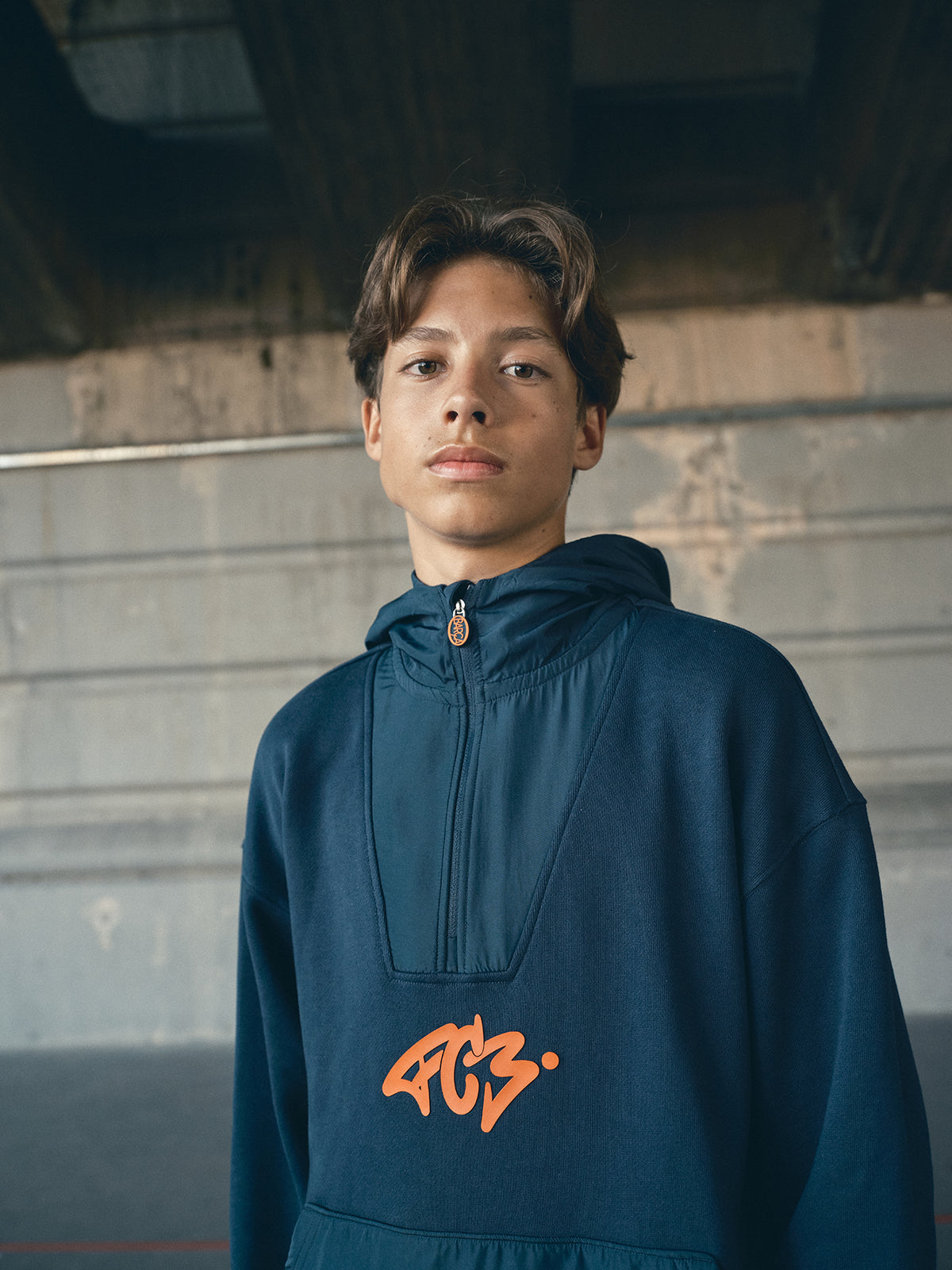 navy blue FC Barcelona hoodie featuring a front zipper and an orange graffiti-style 'FCB' logo printed on the chest